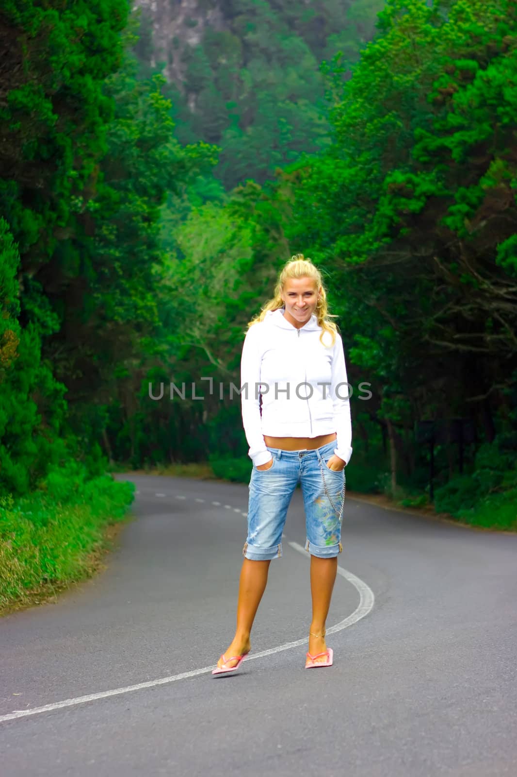 Blond girl standing right in the middle of the mountain road