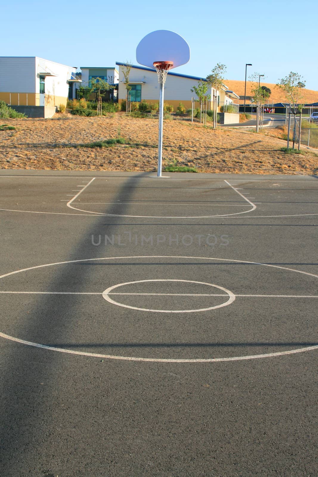 Basketball court on a sunny day in a park.
