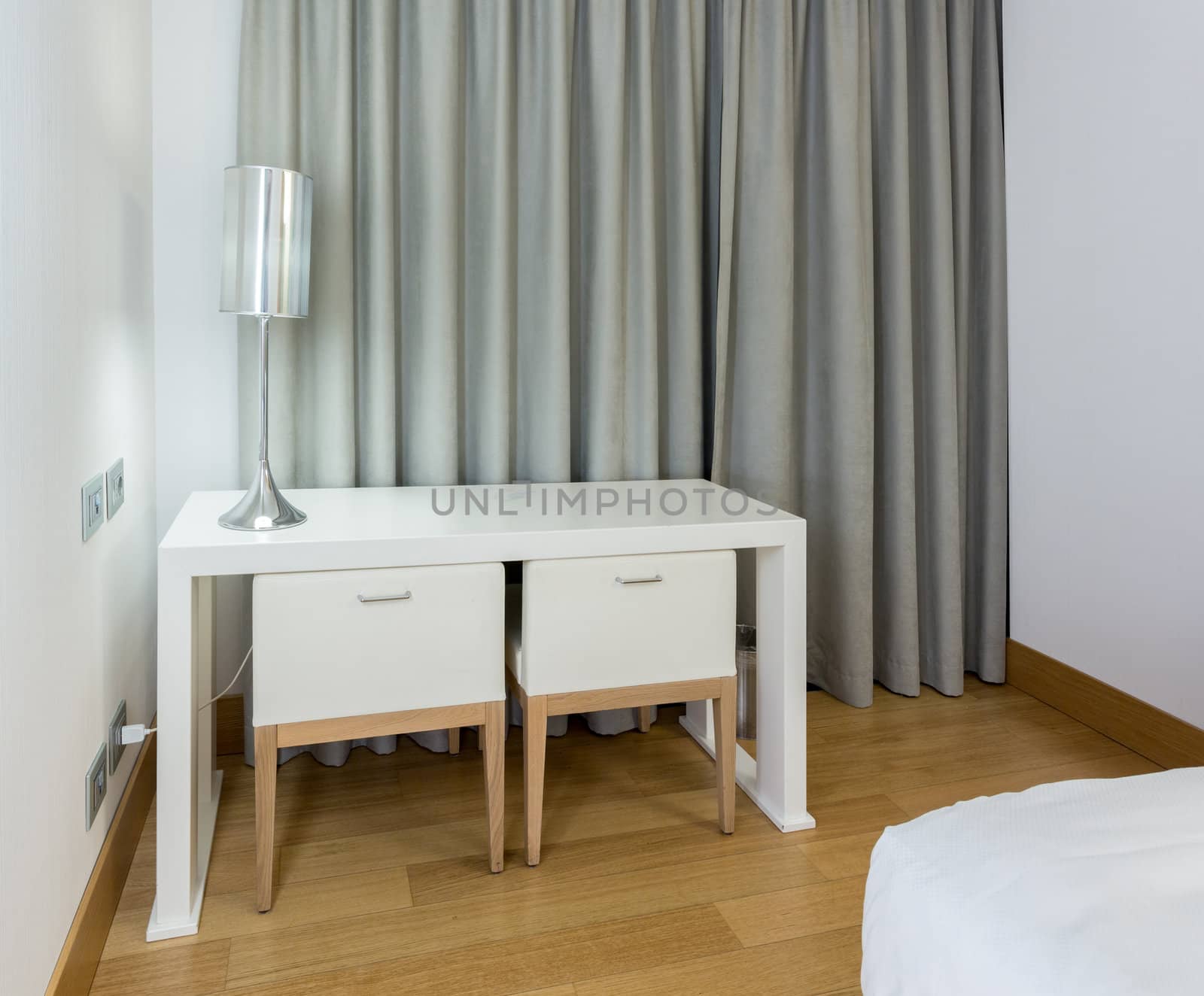 Modern white table desk and two chairs in hotel room at night