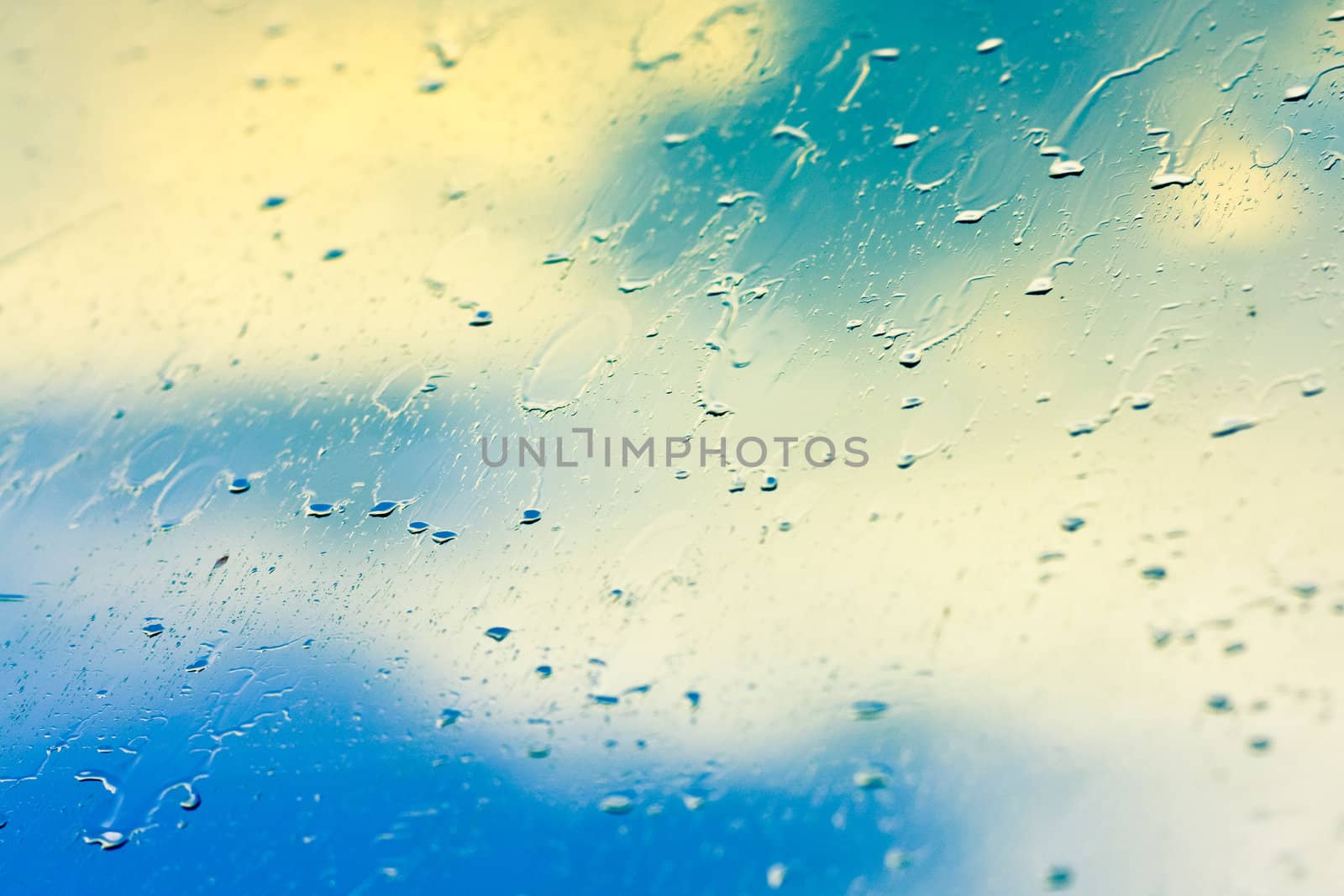 Drops of rain on glass on background of cloudy sky