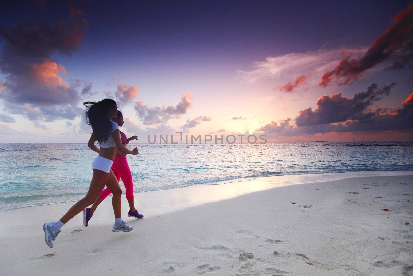 Fitness sport women running on beach at sunset