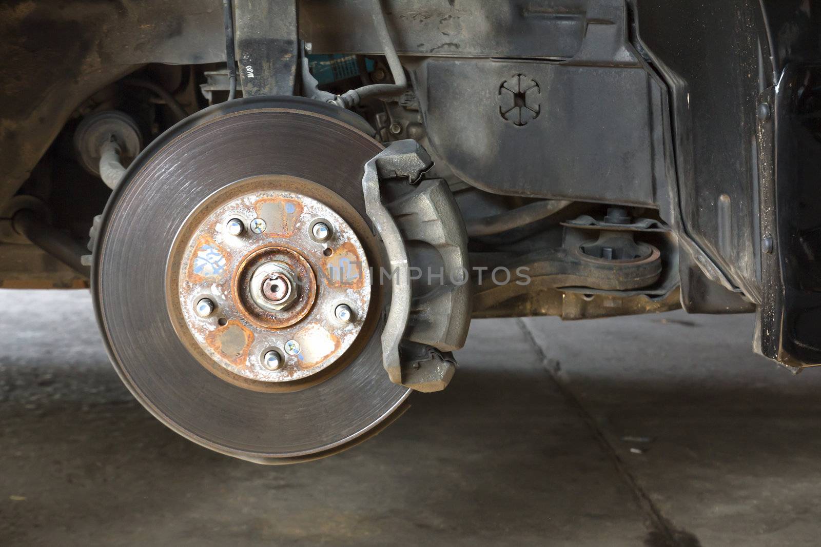 Front disk brake on car in process of damaged tyre replacement. The rim is removed showing the front rotor and caliper.