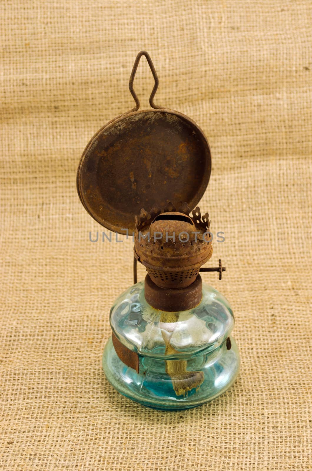 rusty retro kerosene lamp on burlap rural background.