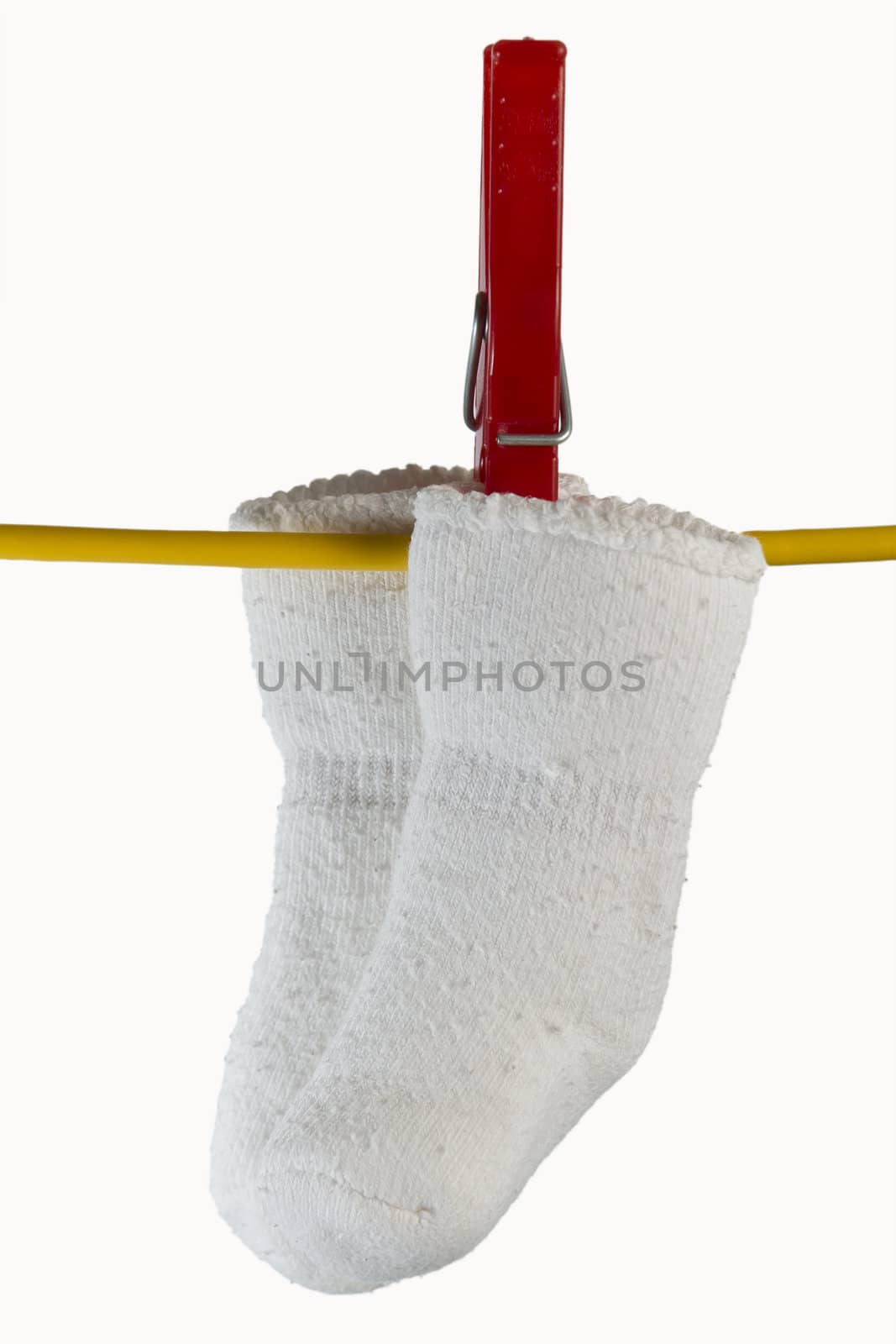 two white baby sox on yellow clothesline with clothespin in white background