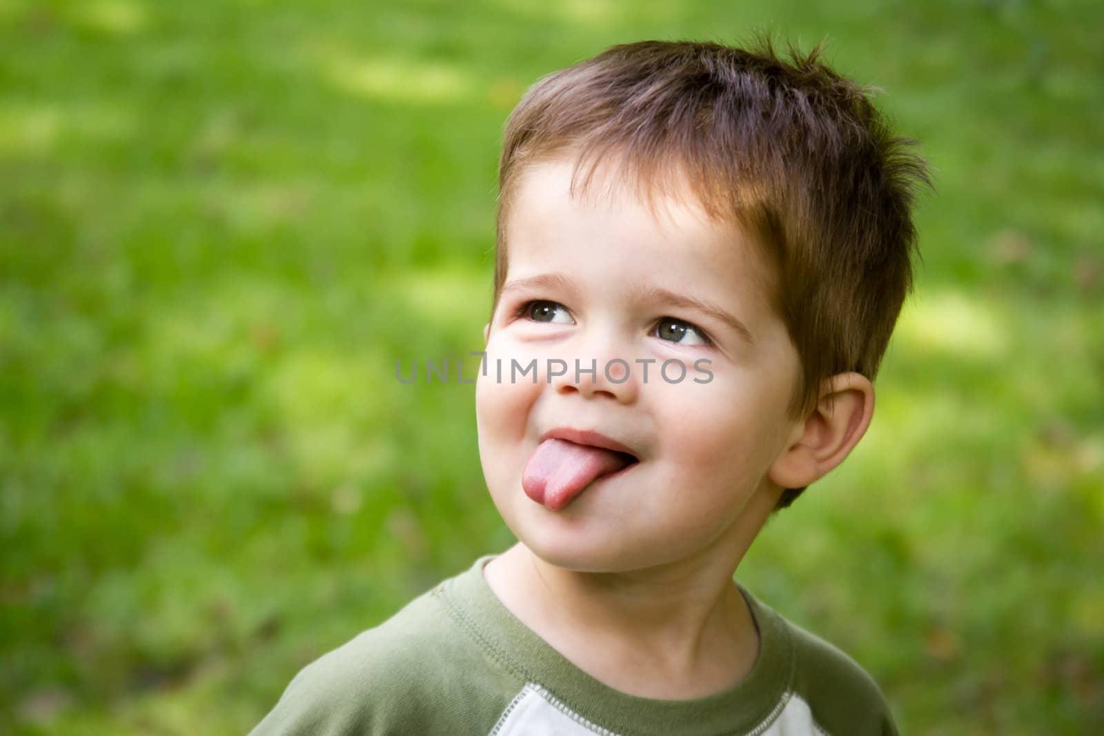 Portrait of a cute little brown-haired, blue-eyed boy sticking out his tongue