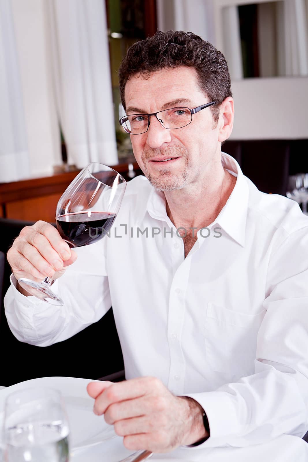 man and woman in restaurant for dinner drinking red wine and smiling