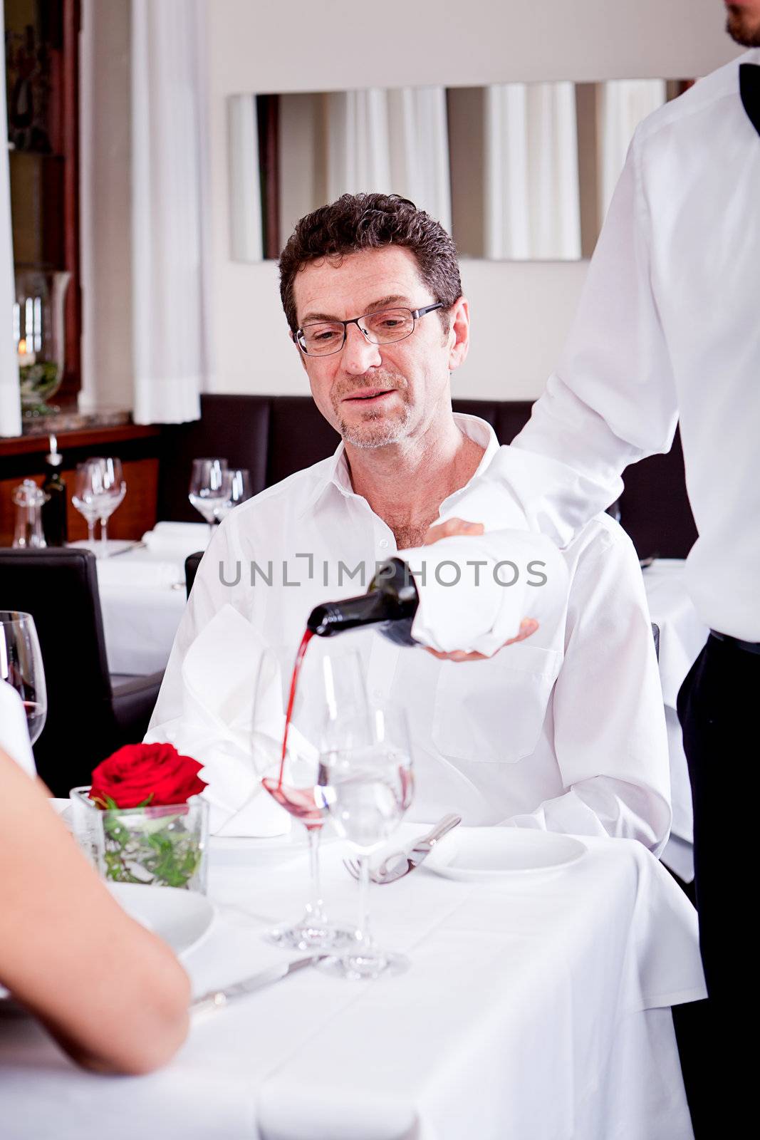 man and woman in restaurant for dinner drinking red wine and smiling