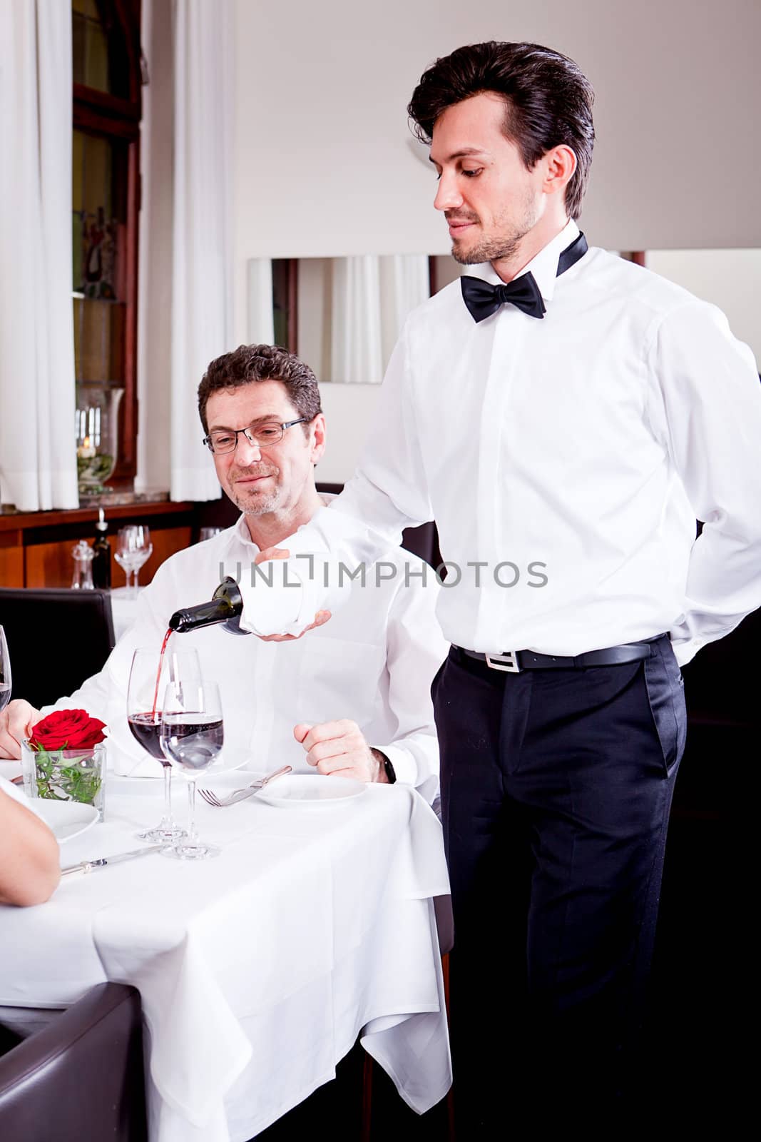 couple drinking red wine in restaurant by juniart
