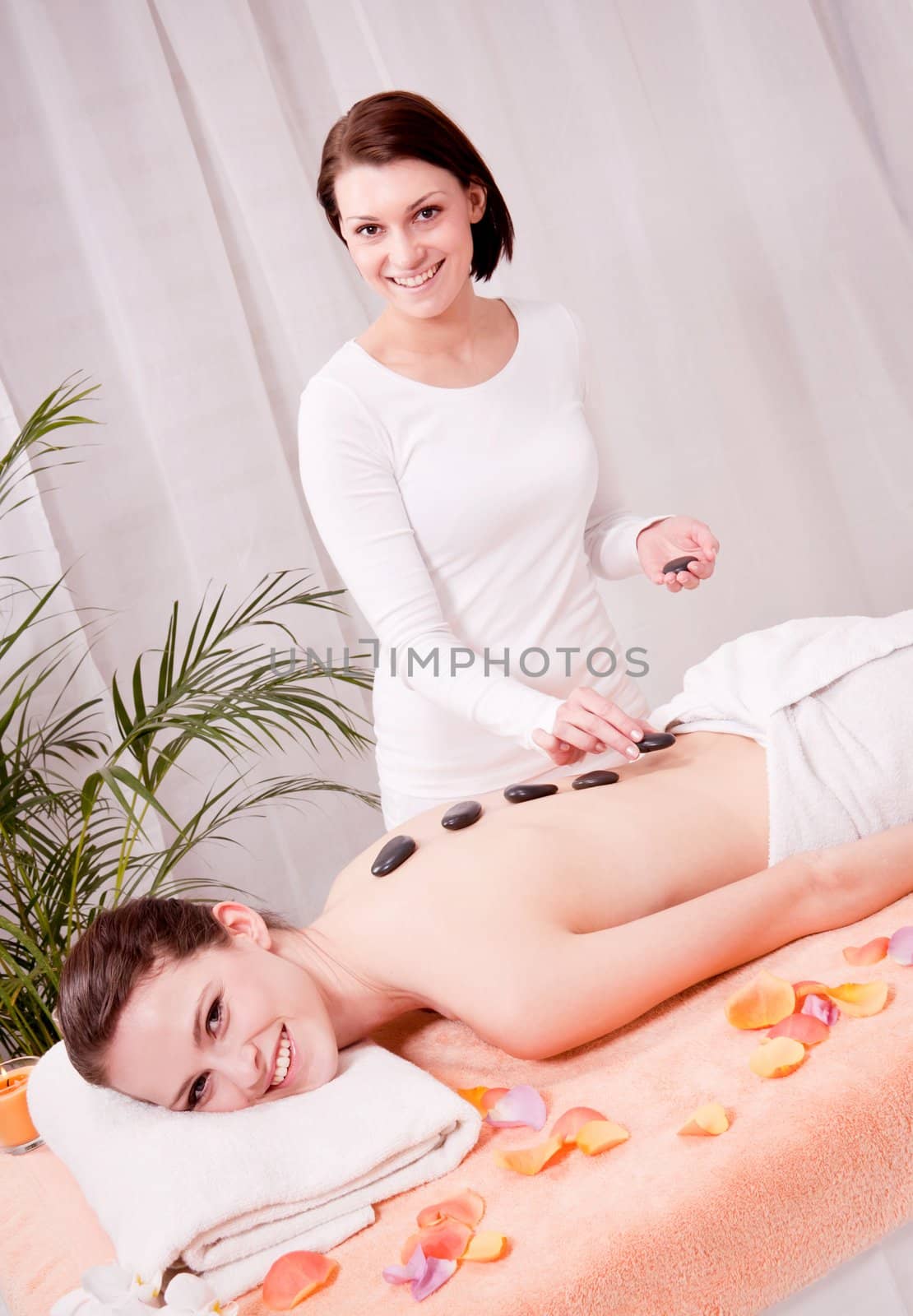 young attractive woman get hot stone massage by professional in wellness spa salon