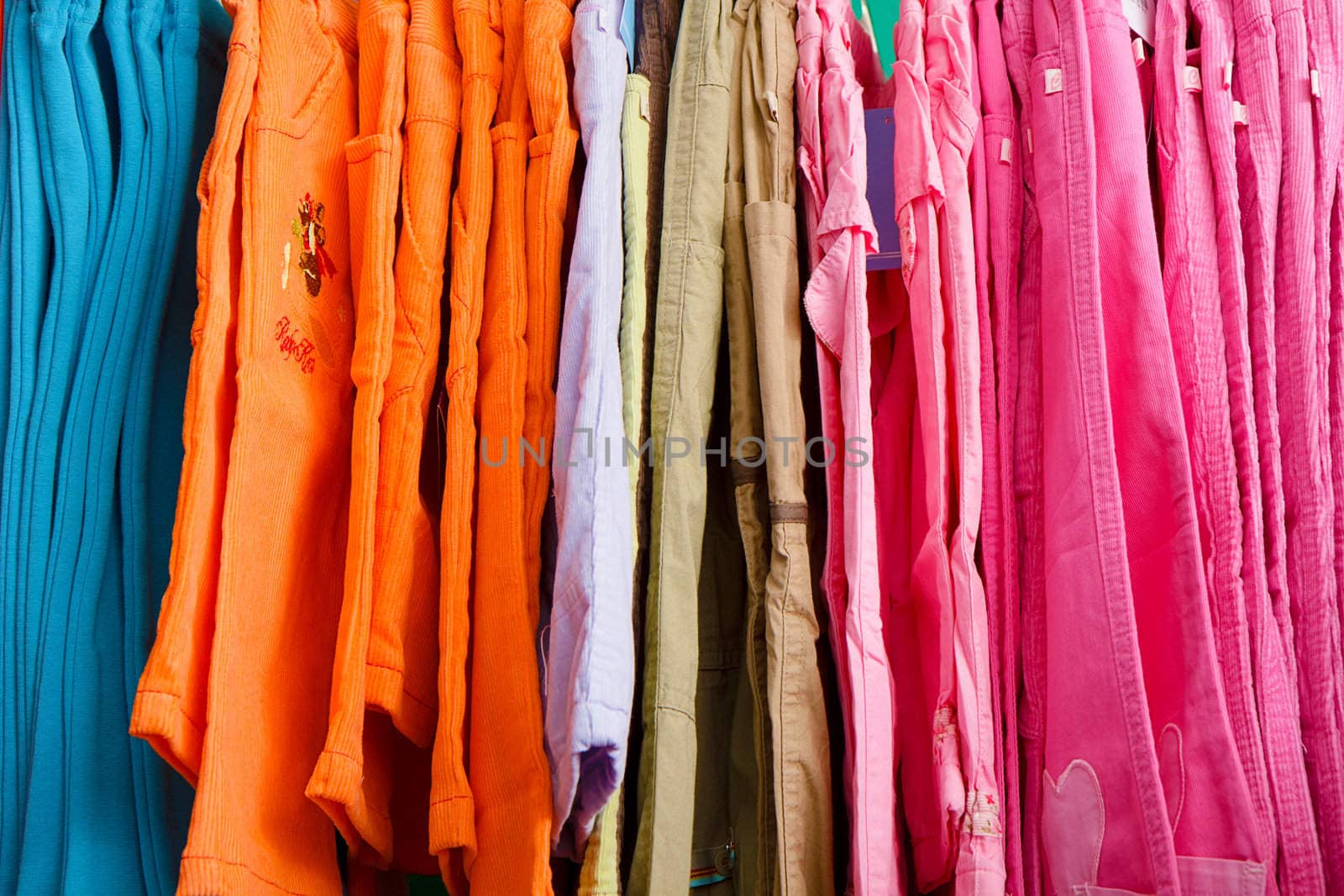 a lot of bright children's clothing on a hanger in the store