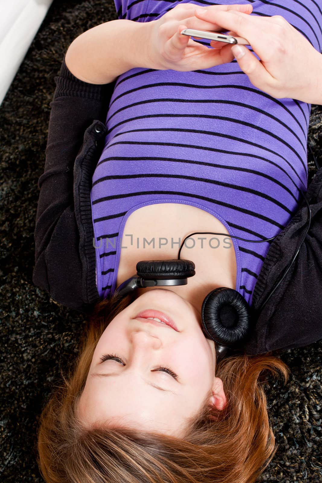 young smiling teenager girl at home with mp3 player and earphones listening to music