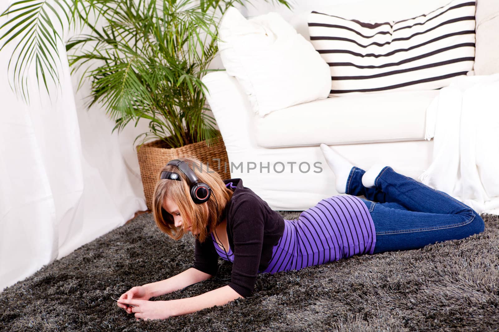 young smiling teenager girl at home with mp3 player and earphones listening to music