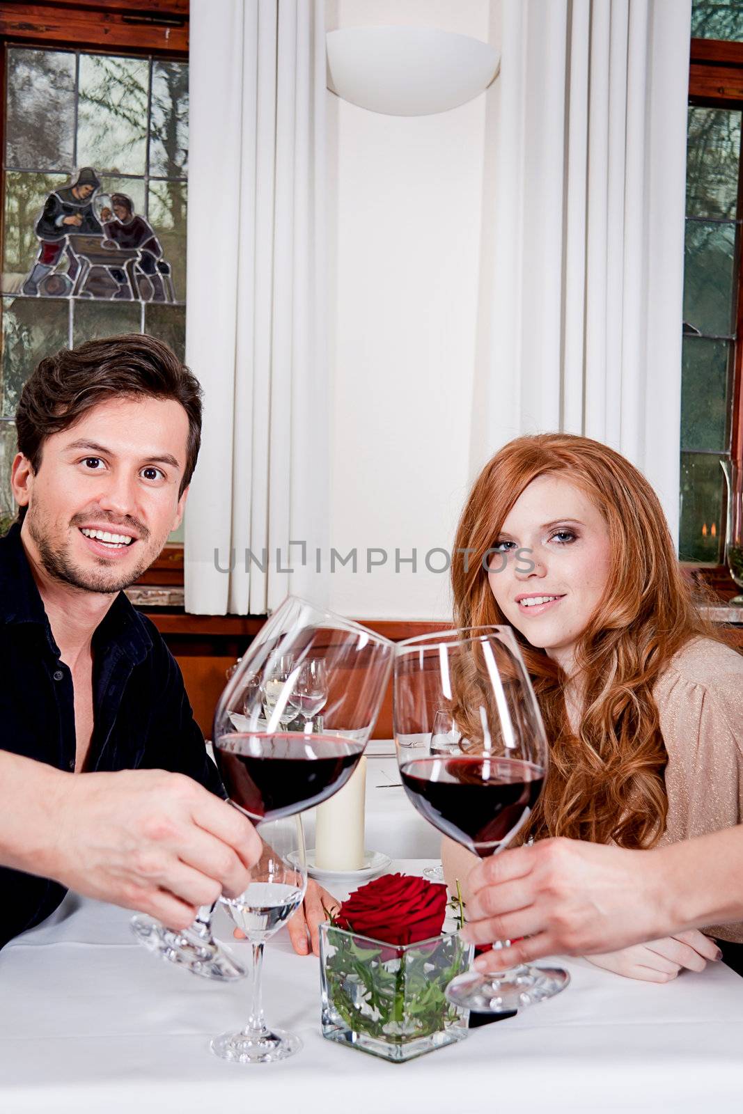 man and woman in restaurant for dinner drinking red wine and smiling