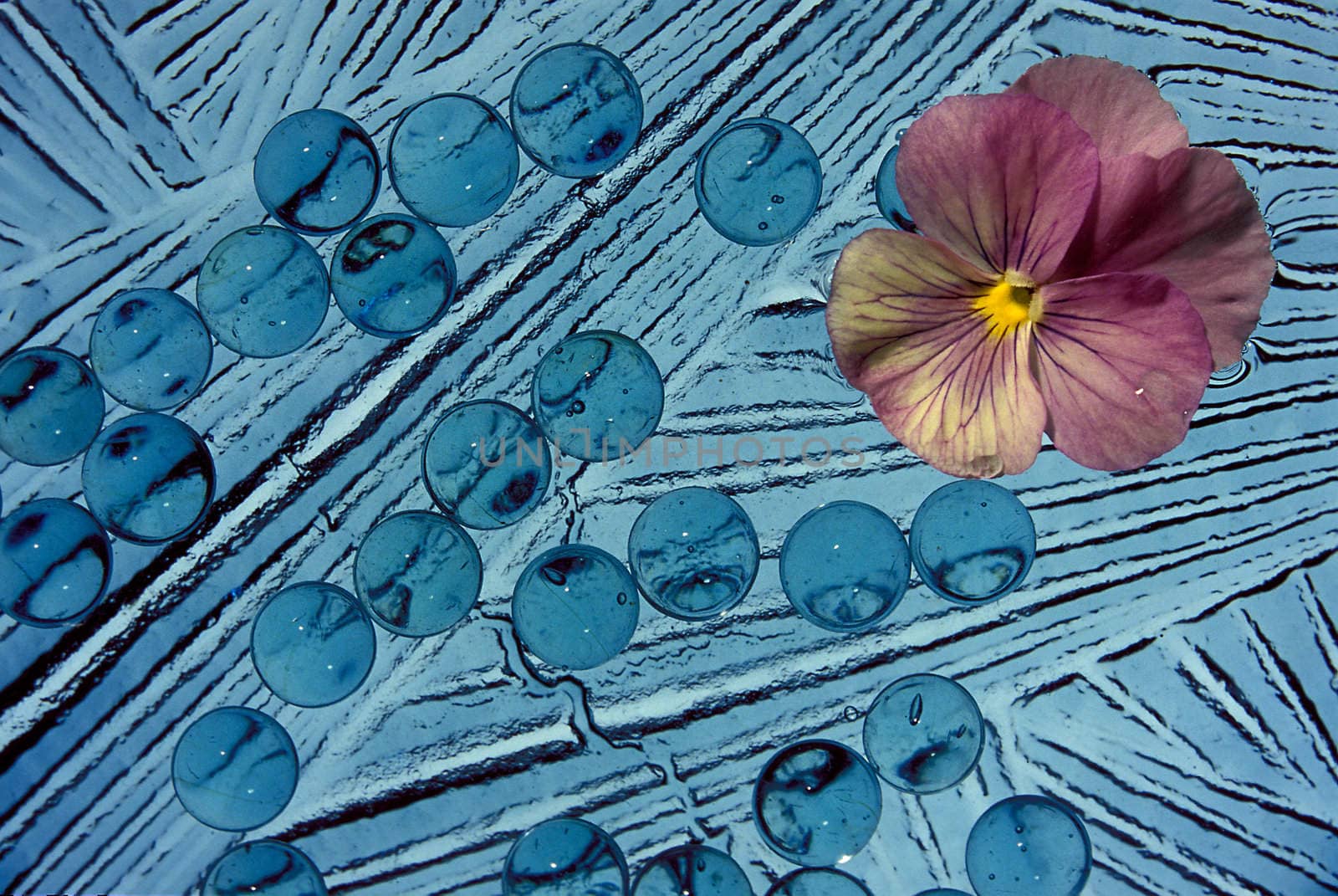 A blue abstract with a pink flower in the upper right corner