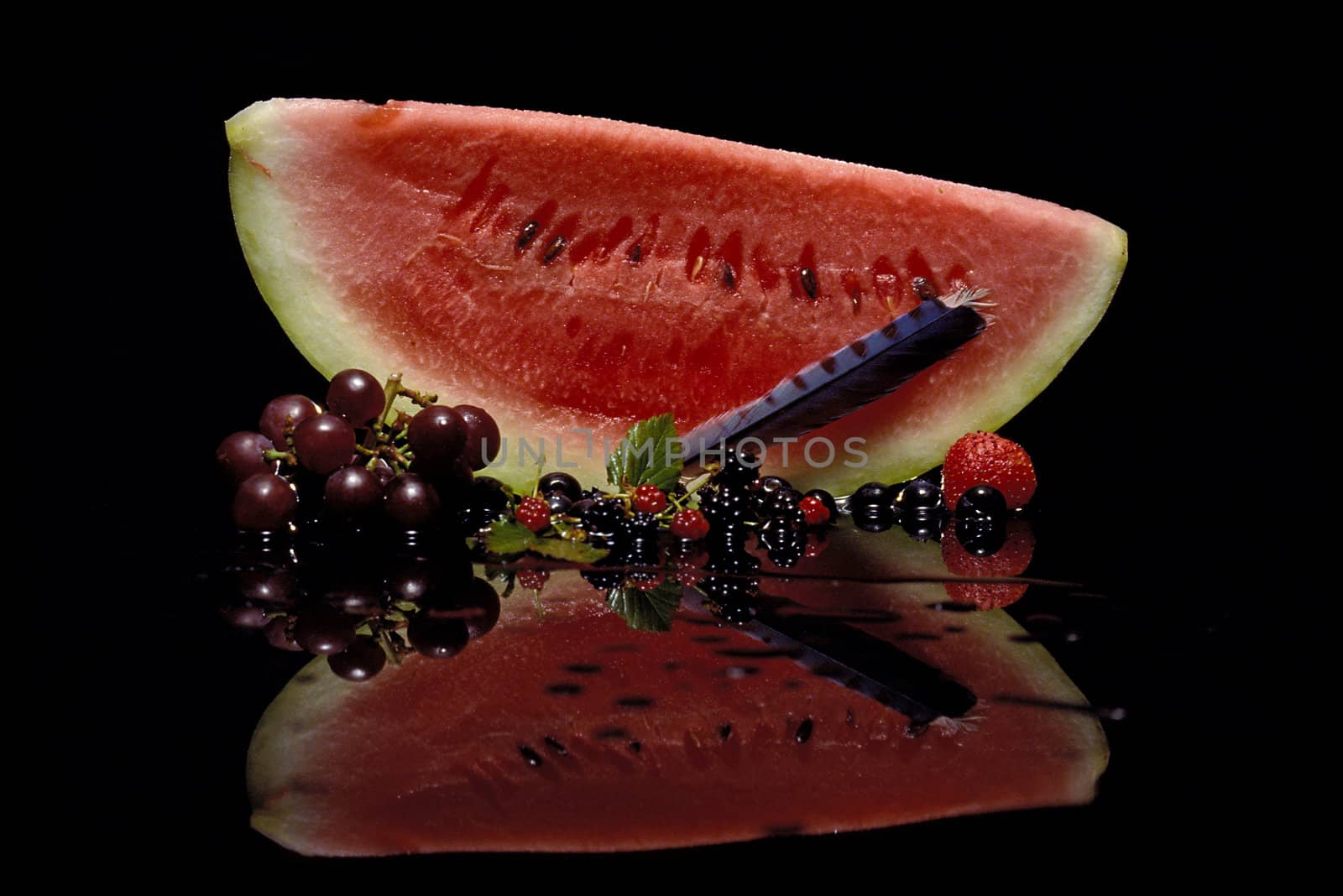 A slice of watermelon with mixed fruit on a reflective background