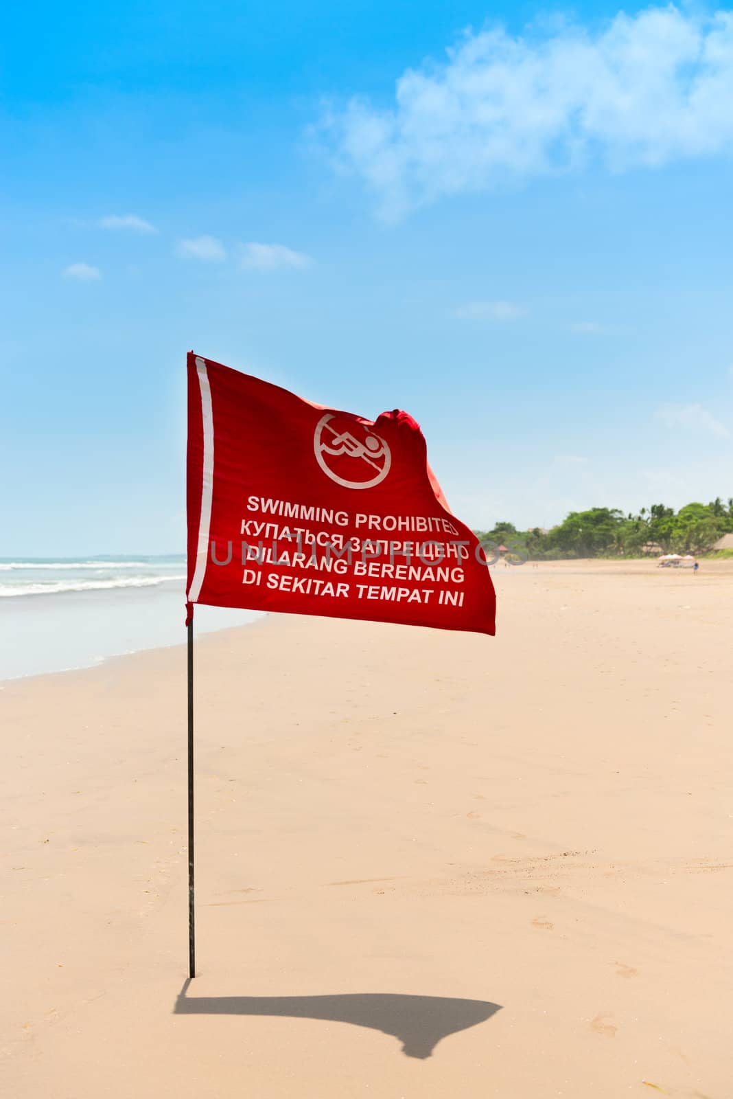 Season of storms. Red flag on the sand beach with no Swimming sign .