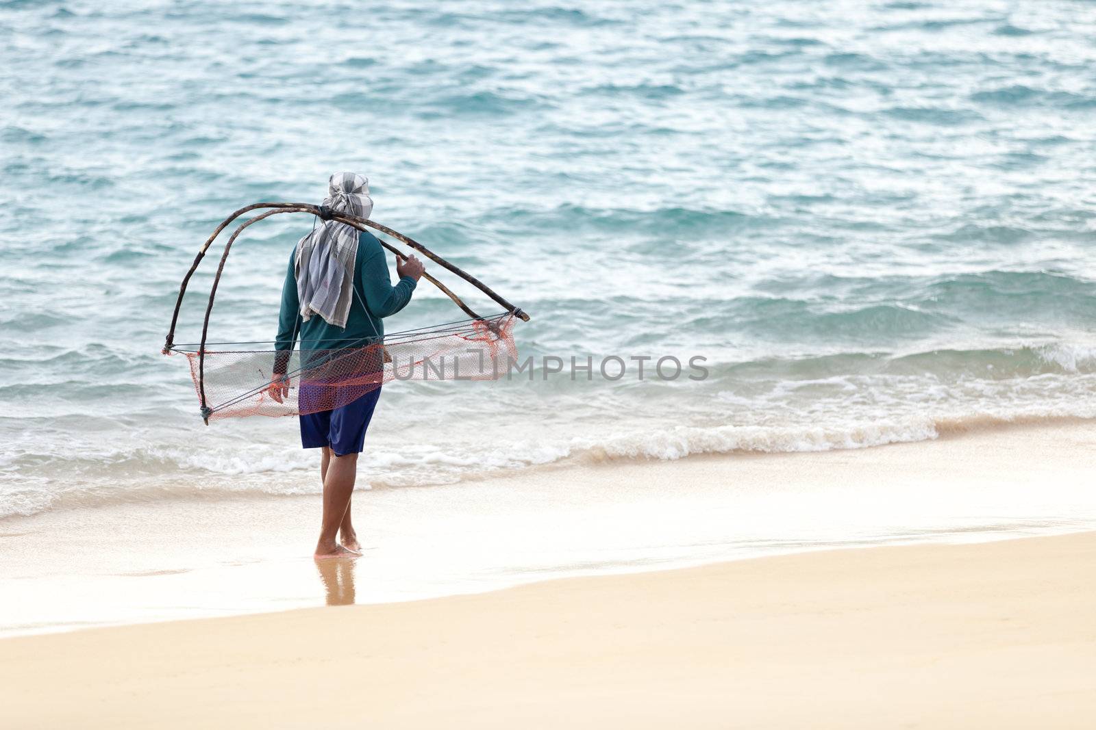 Man with net walk on the sea sand coast, Thailand