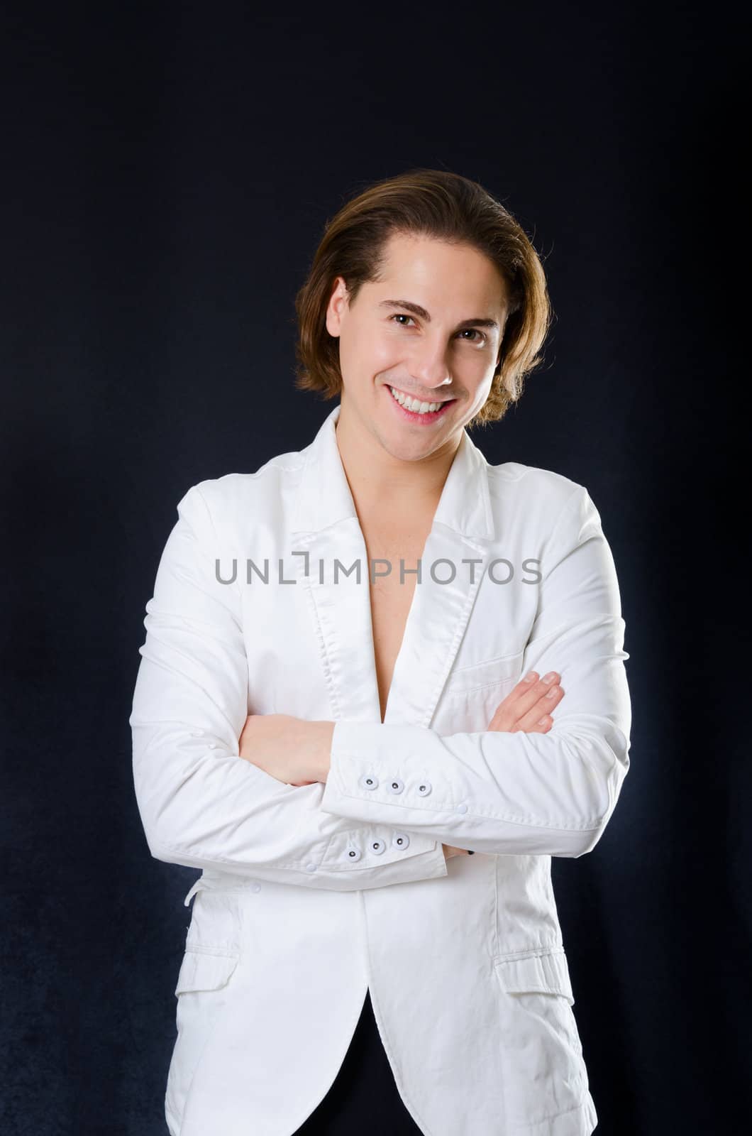 Young smiling man macho in white jacket on dark background 