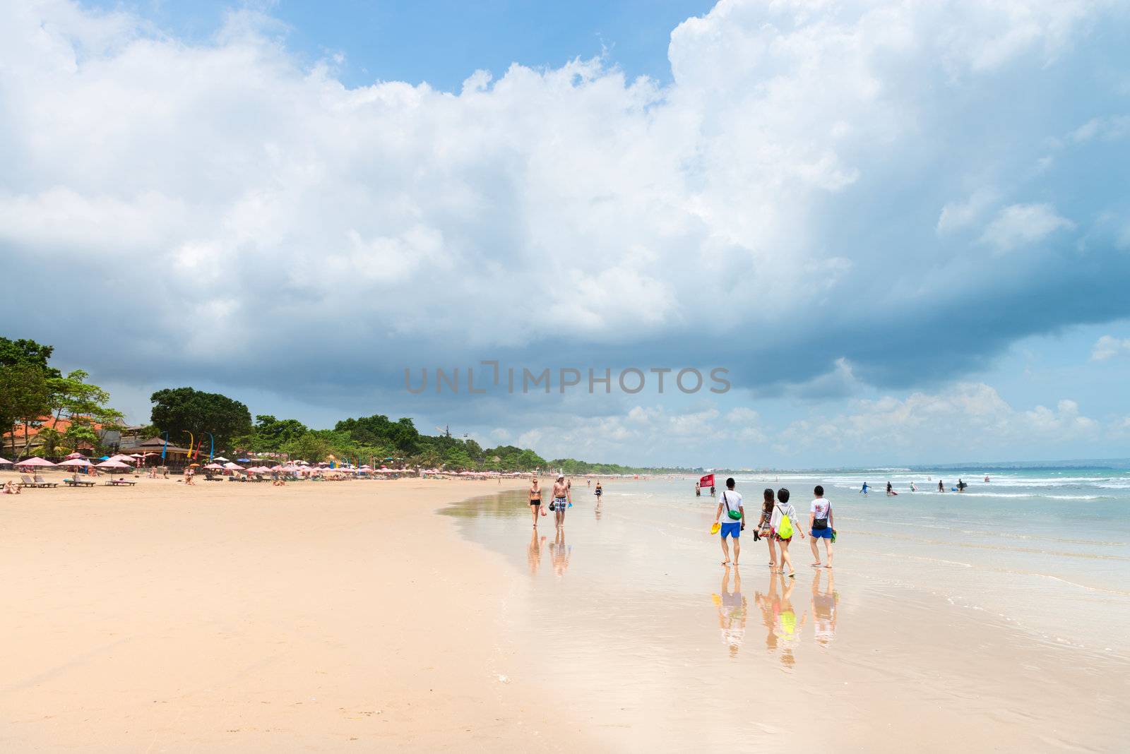 SEMINYAK, BALI - SEP 27: Wide sand beach with tourists, umbrellas and beds on Sep 27, 2012 in Seminyak, Bali, Indonesia. The five km long sandy stretch of Kuta is arguably the best beach front in Bali.  