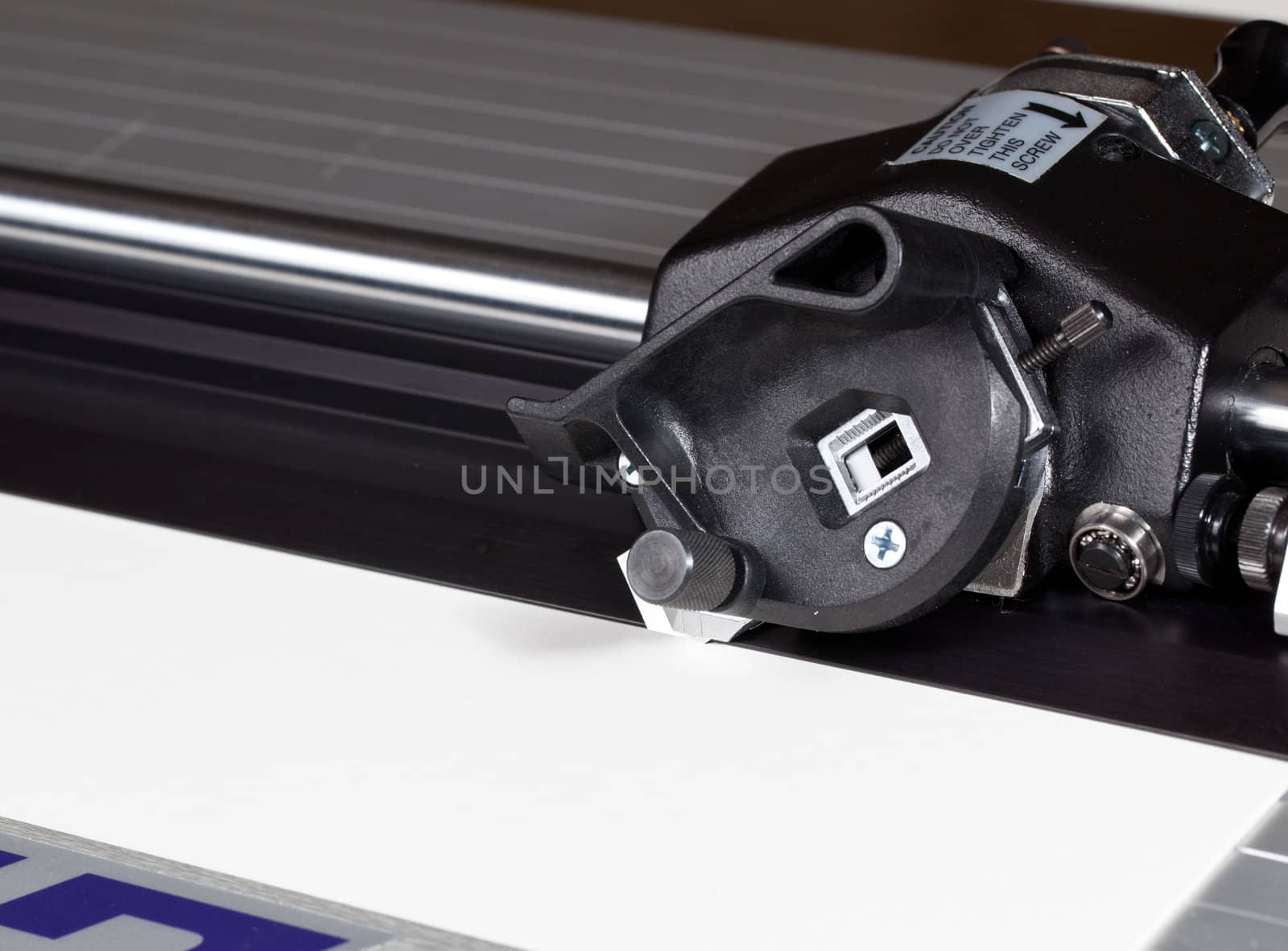 Blade of mat cutter cutting into a white mat for framing a picture