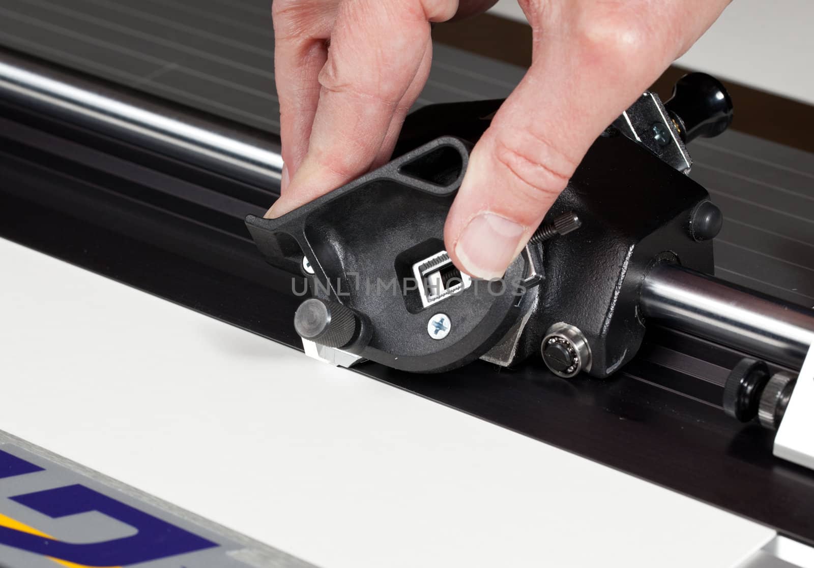 Hand on blade of mat cutter cutting into a white mat for framing a picture