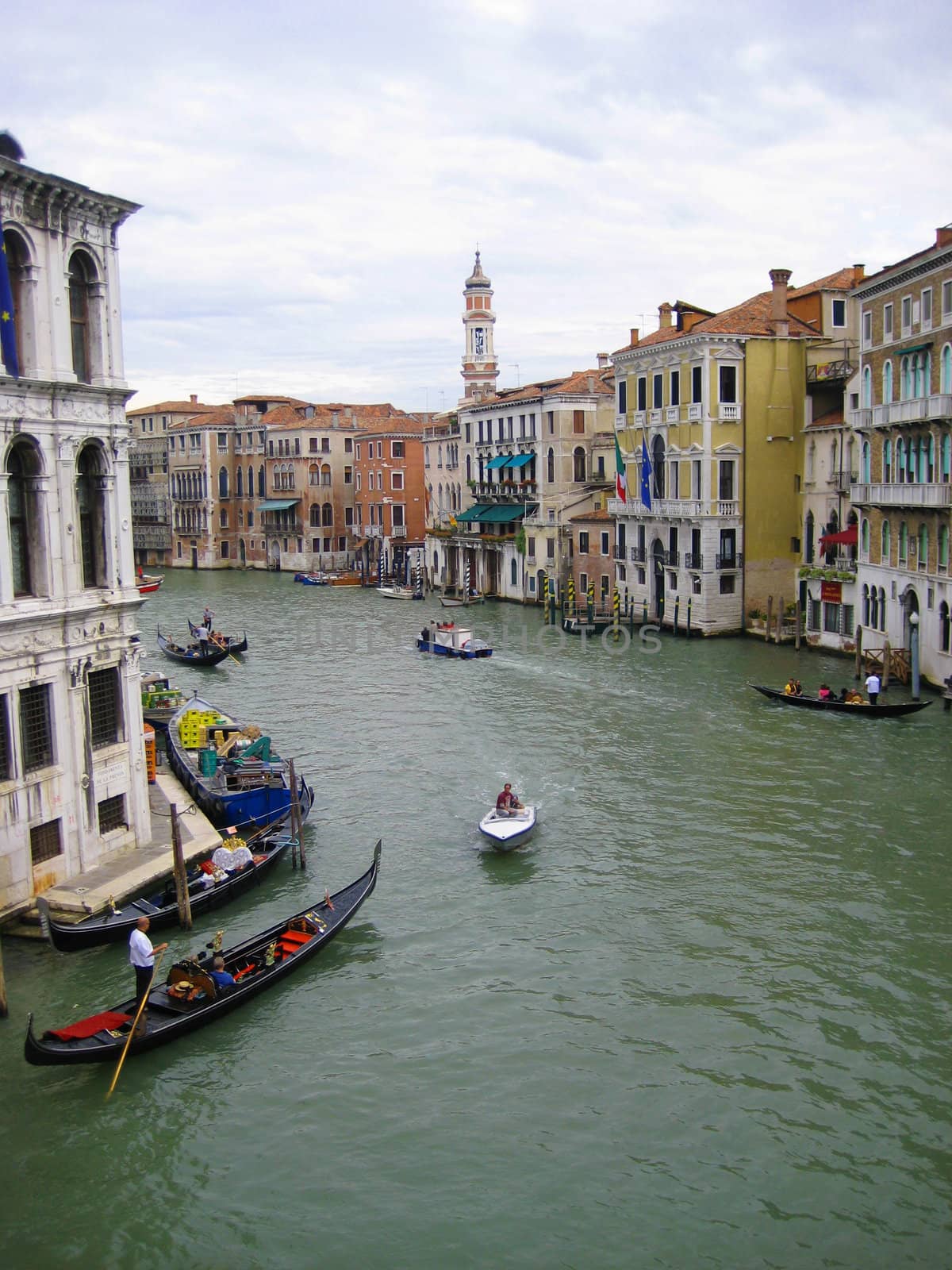 A scene of gondolas gliding through the canals of Venice, Italy. There is also Italian architecture and buildings visible.