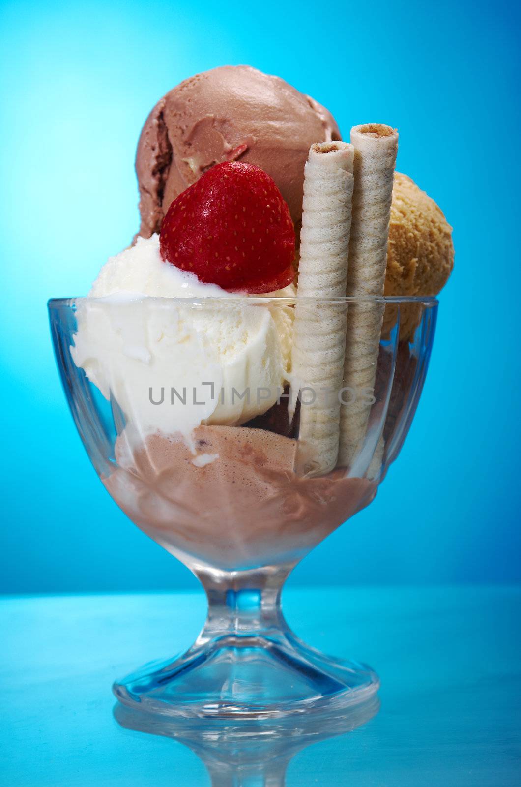 ice cream in with strawberries and chocolate. closeup .on blue background.