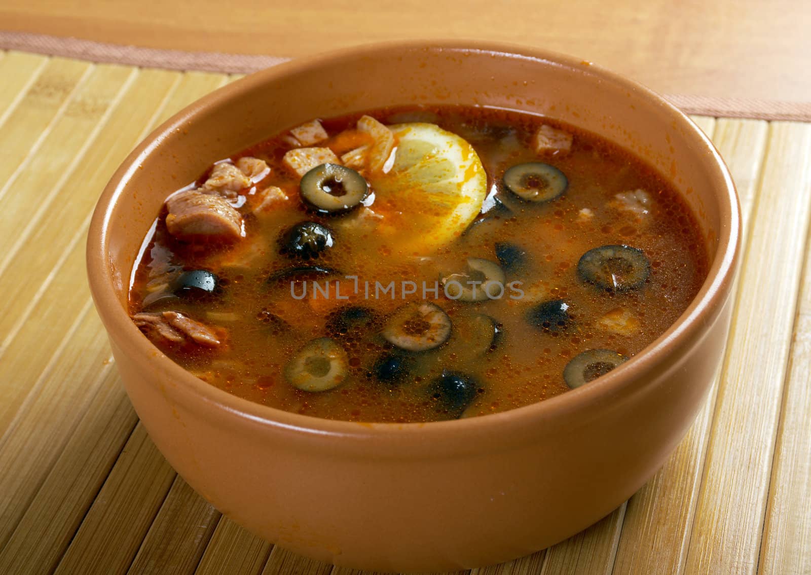 Solyanka on the plate.Solyanka, Russian soup with beef,sausage,chicken and lemon, olives