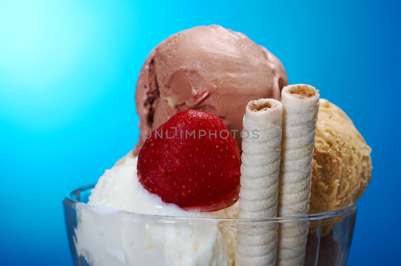 ice cream in with strawberries and chocolate. closeup .on blue background.