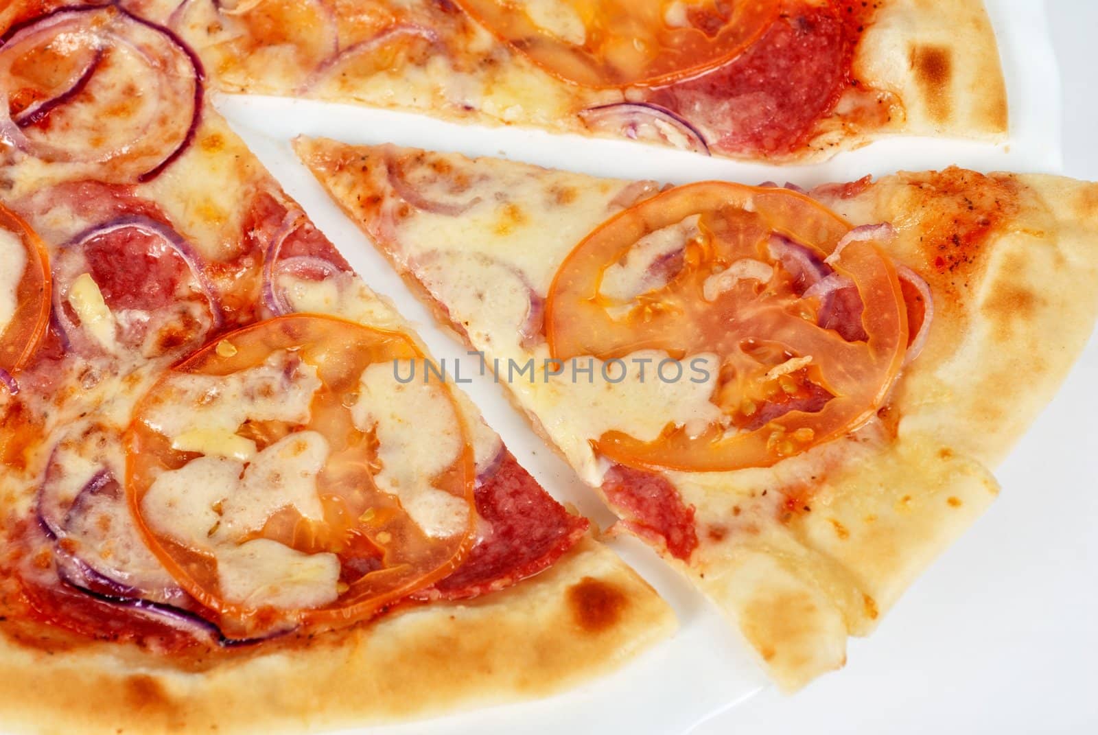 pizza closeup with salami, tomato, onion and mozzarella cheese