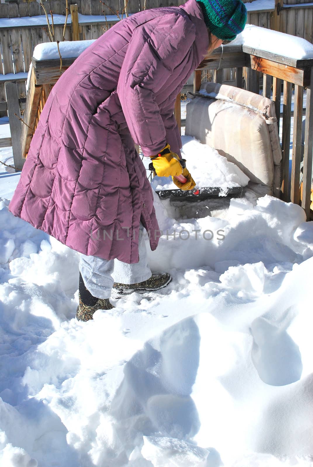 Mature female shoveling snow off her patio deck.