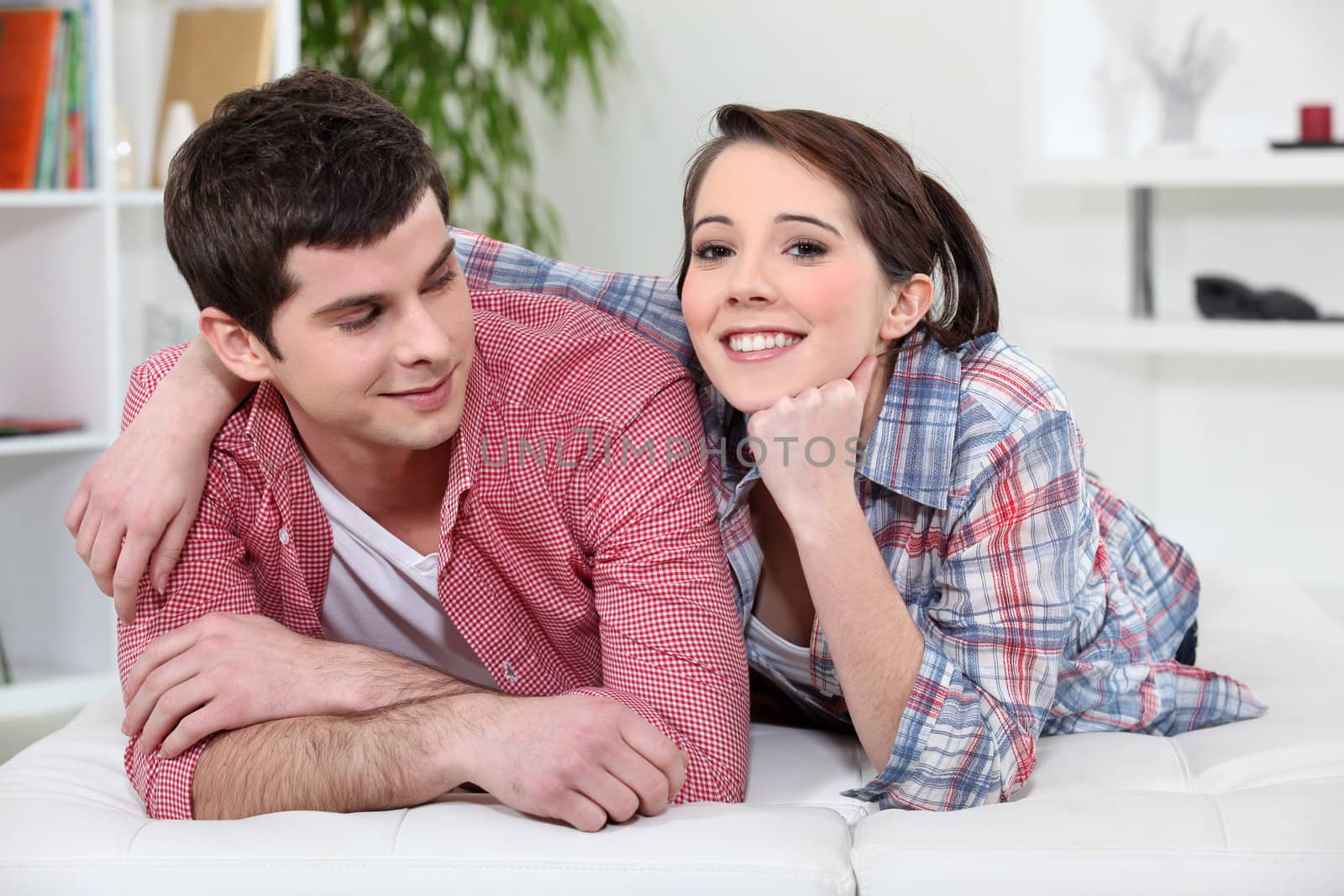 young couple relaxing on the couch by phovoir