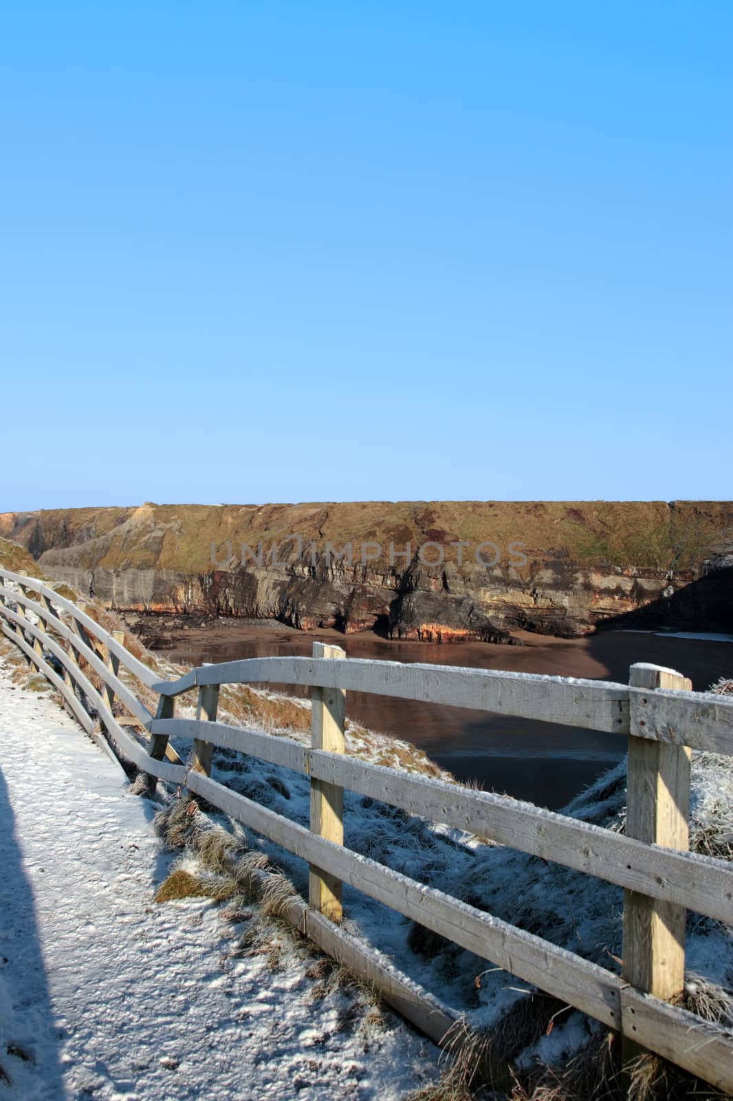 frosty blue winters view at ballybunion cliffside walk with bright sunshine and fence