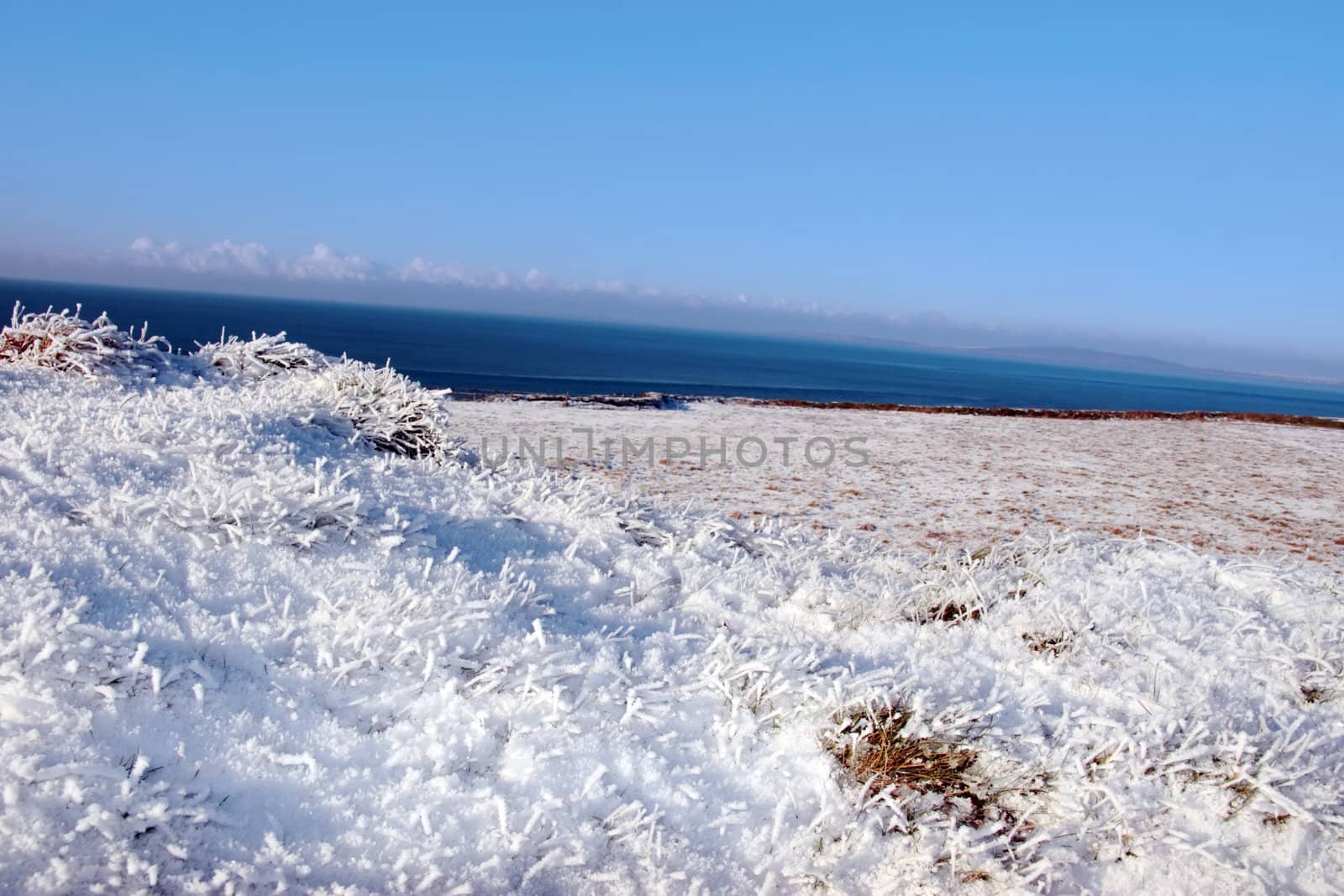 a seasonal snow frosty covered grass ditch with a view of the atlantic ocean