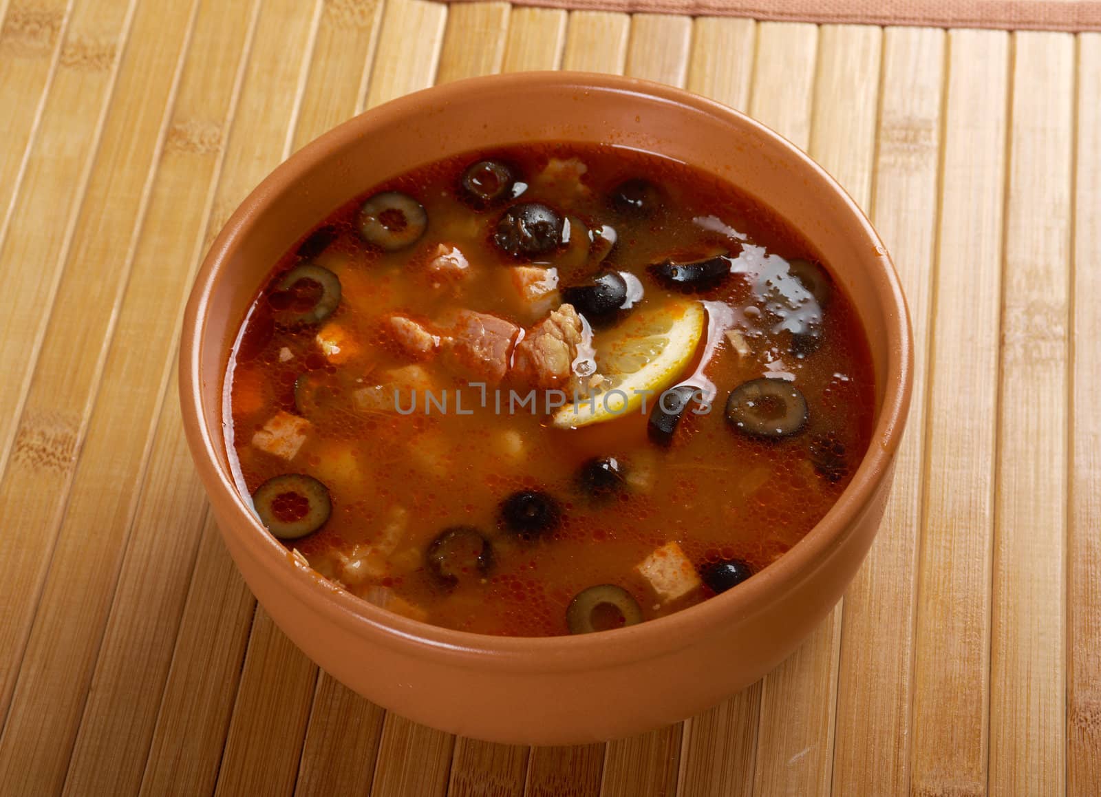 Solyanka on the plate.Solyanka, Russian soup with beef,sausage,chicken and lemon, olives