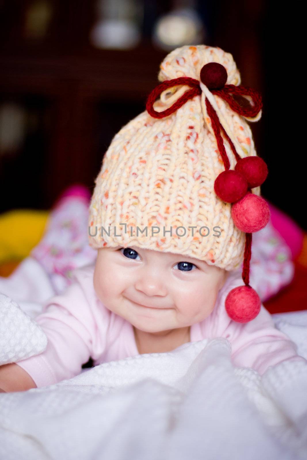 cute happy  baby girl in yellow hat with colourfu bobbles
