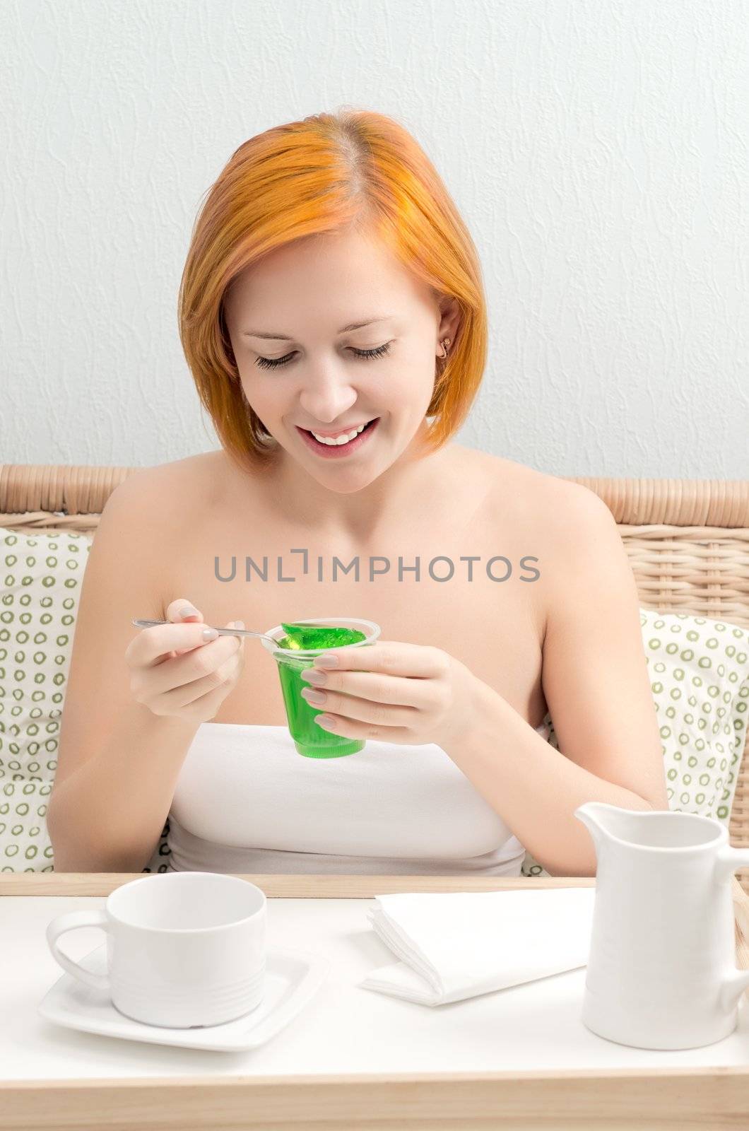 Young red woman in bed having breakfast