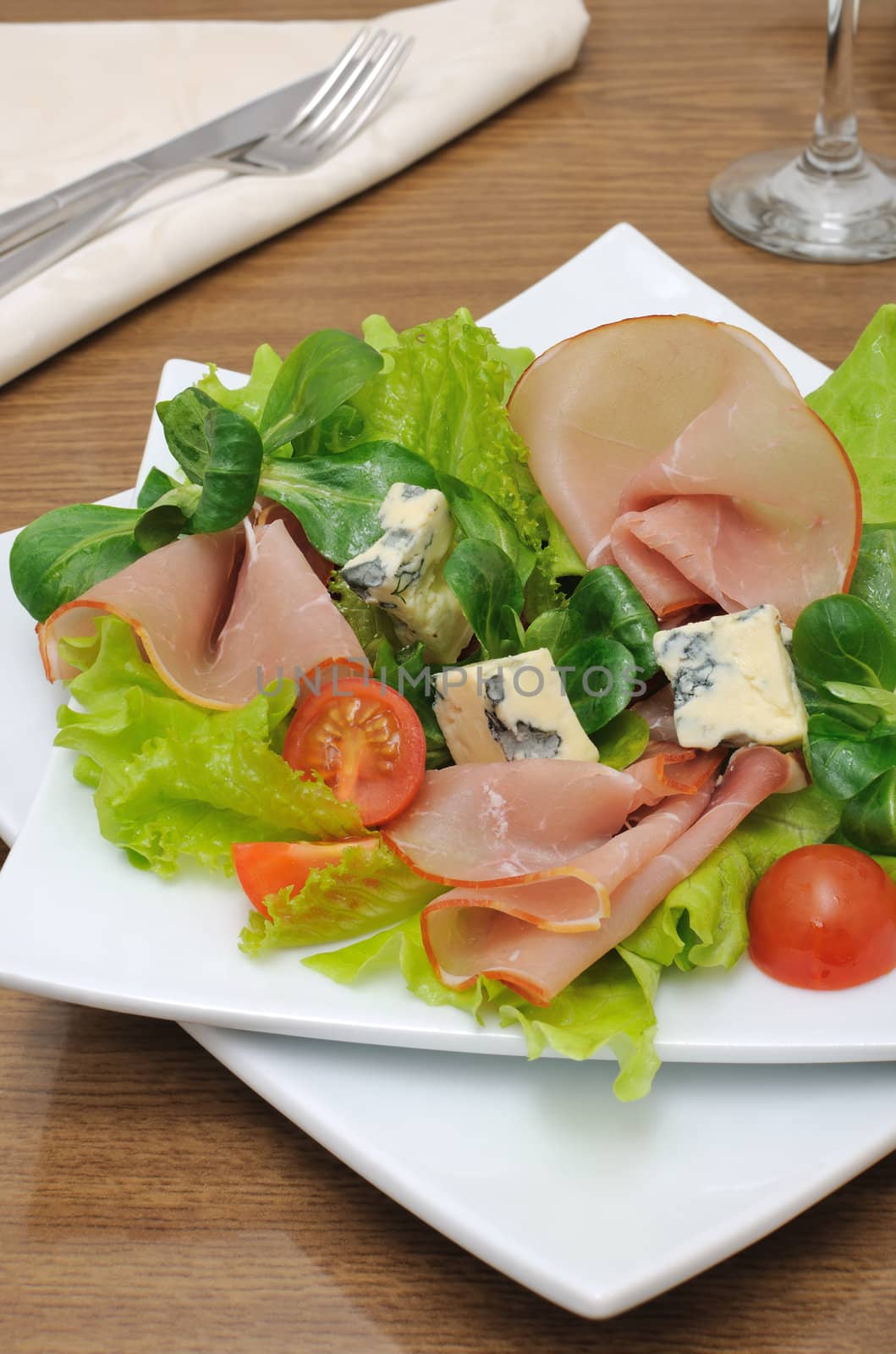 Appetizer with ham and blue cheese in lettuce leaves with corn salad

