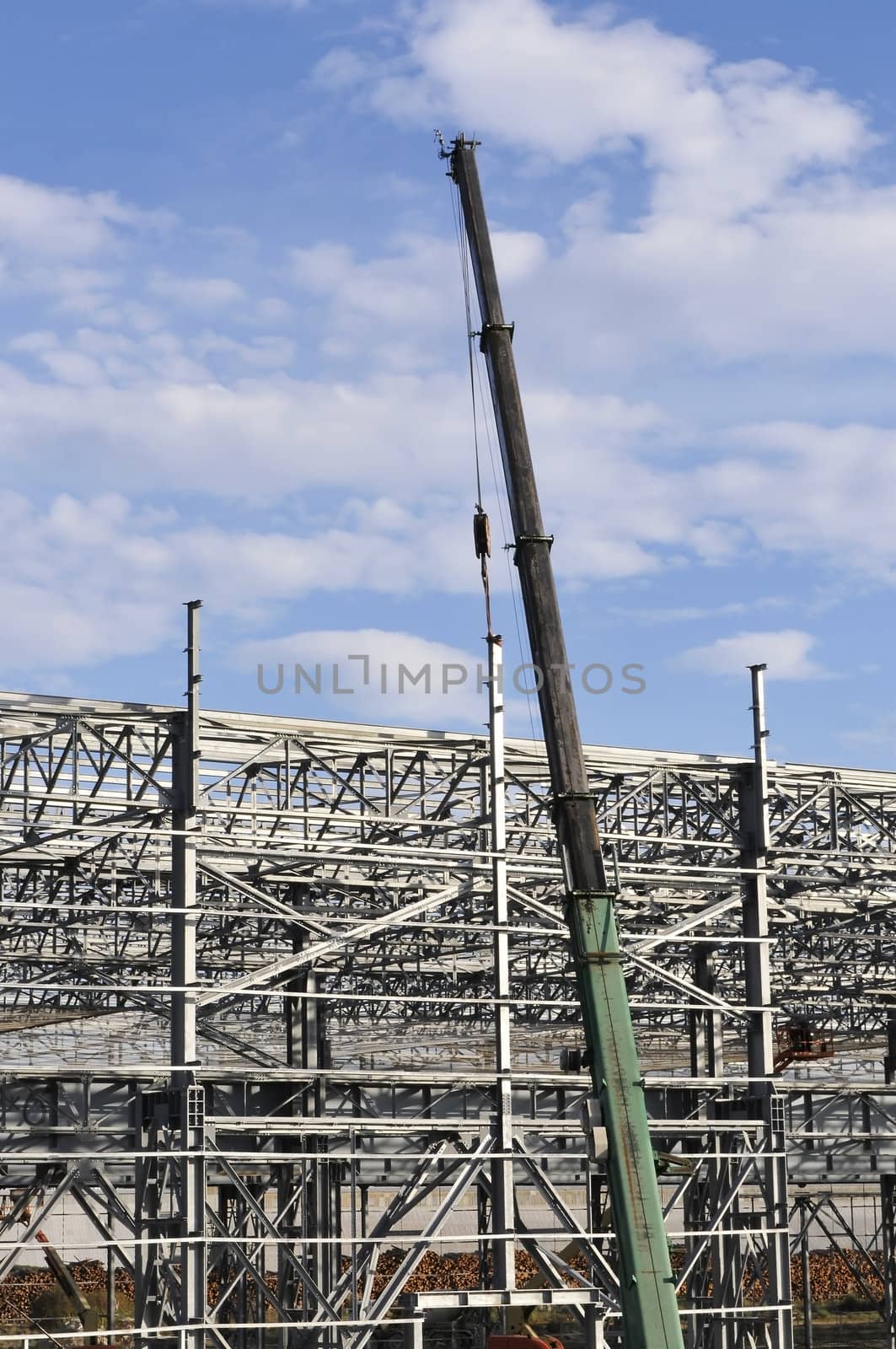 Crane above metallic building structures in a yard with a blue sky