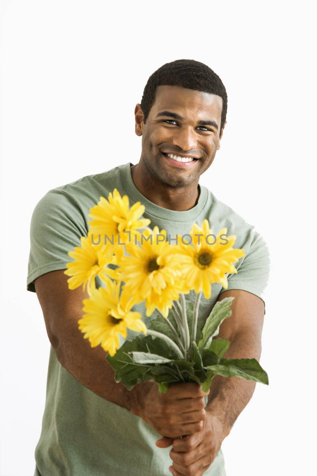 Smiling African American male holding out bouquet of yellow flowers to unseen person.