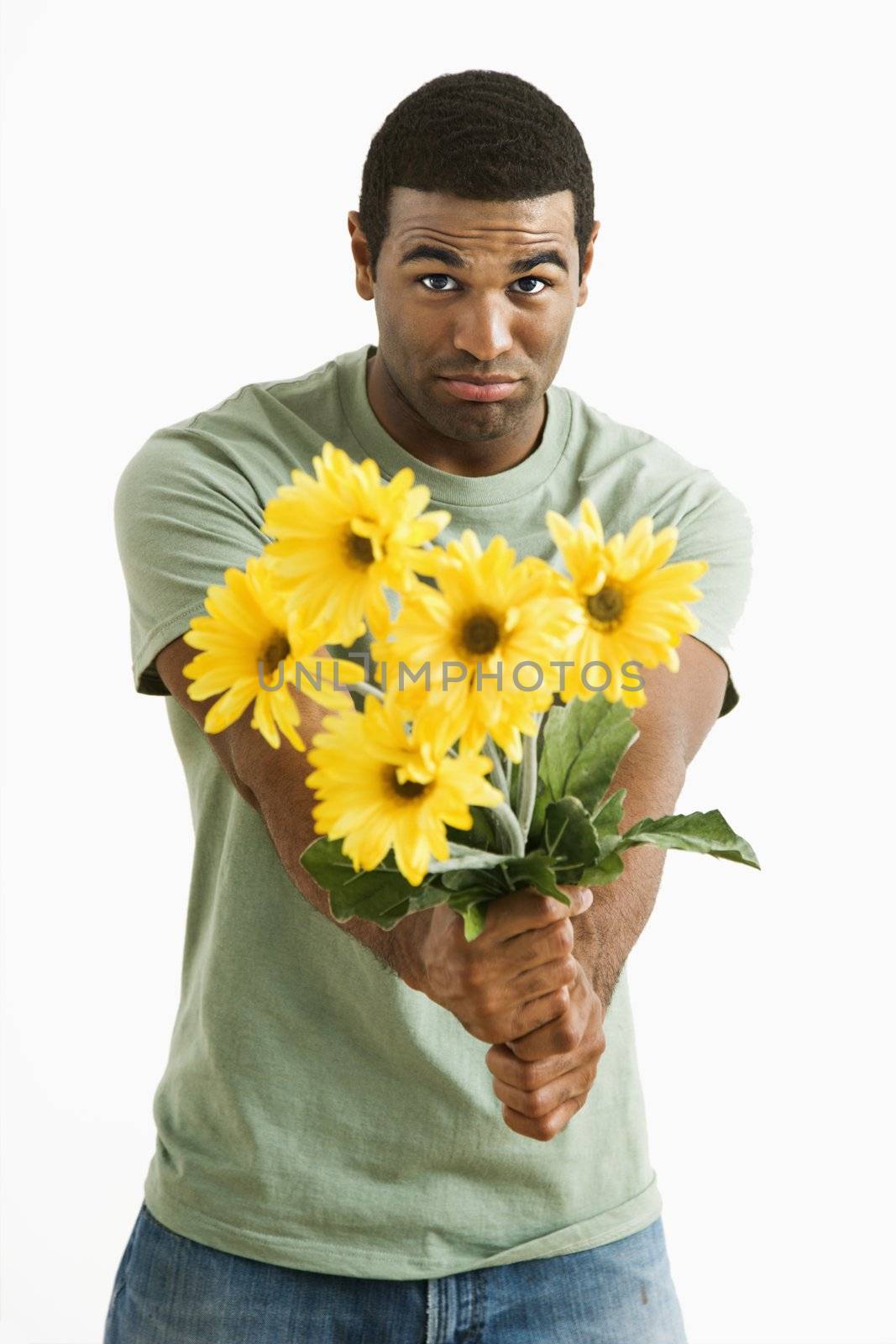 Pouting African American male holding out bouquet of yellow flowers to unseen person.