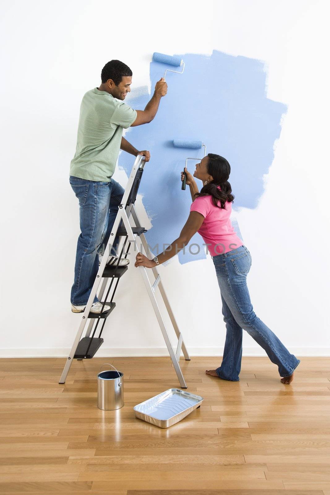 Couple painting wall blue. by iofoto