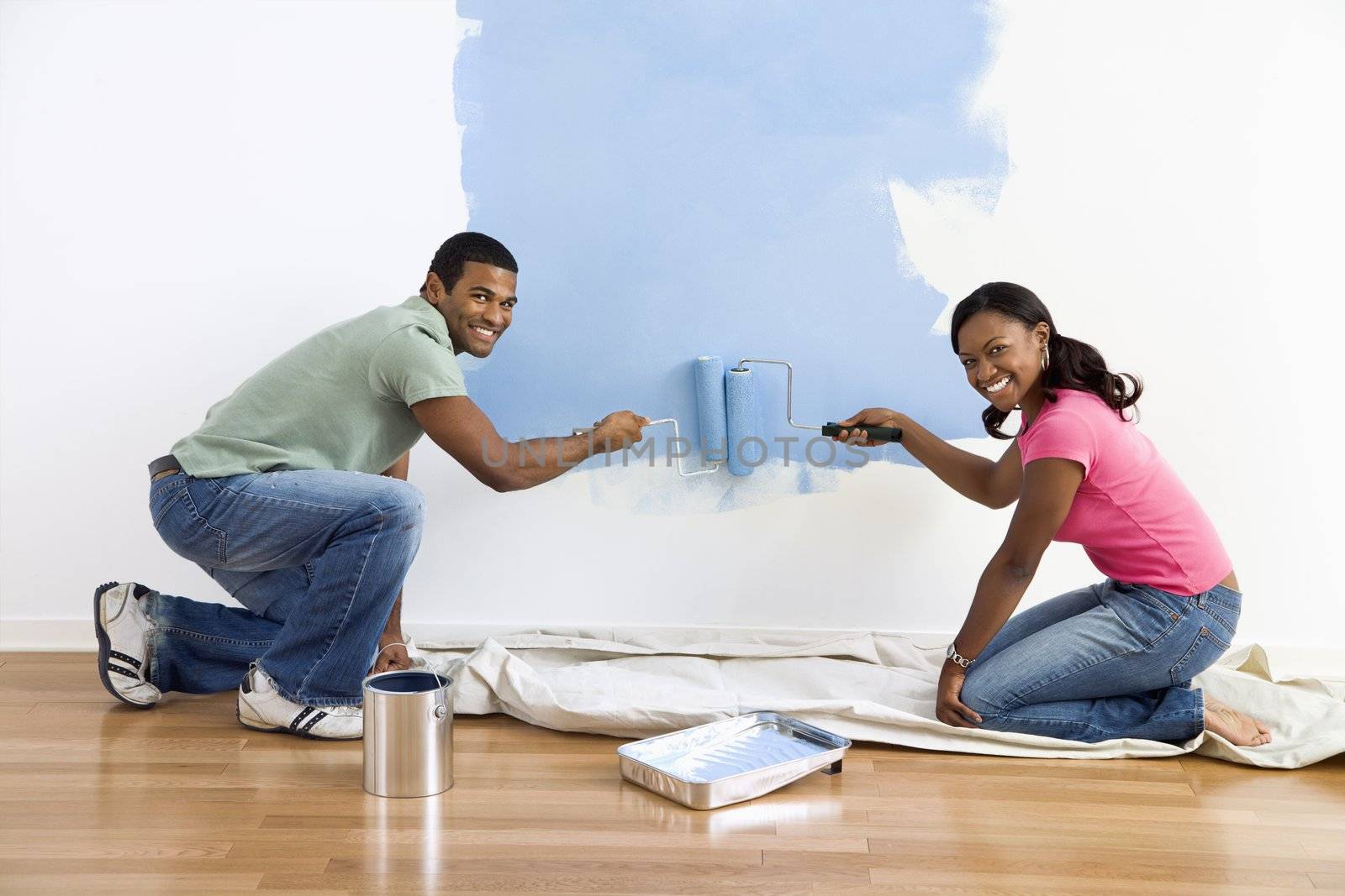 Couple painting wall blue. by iofoto