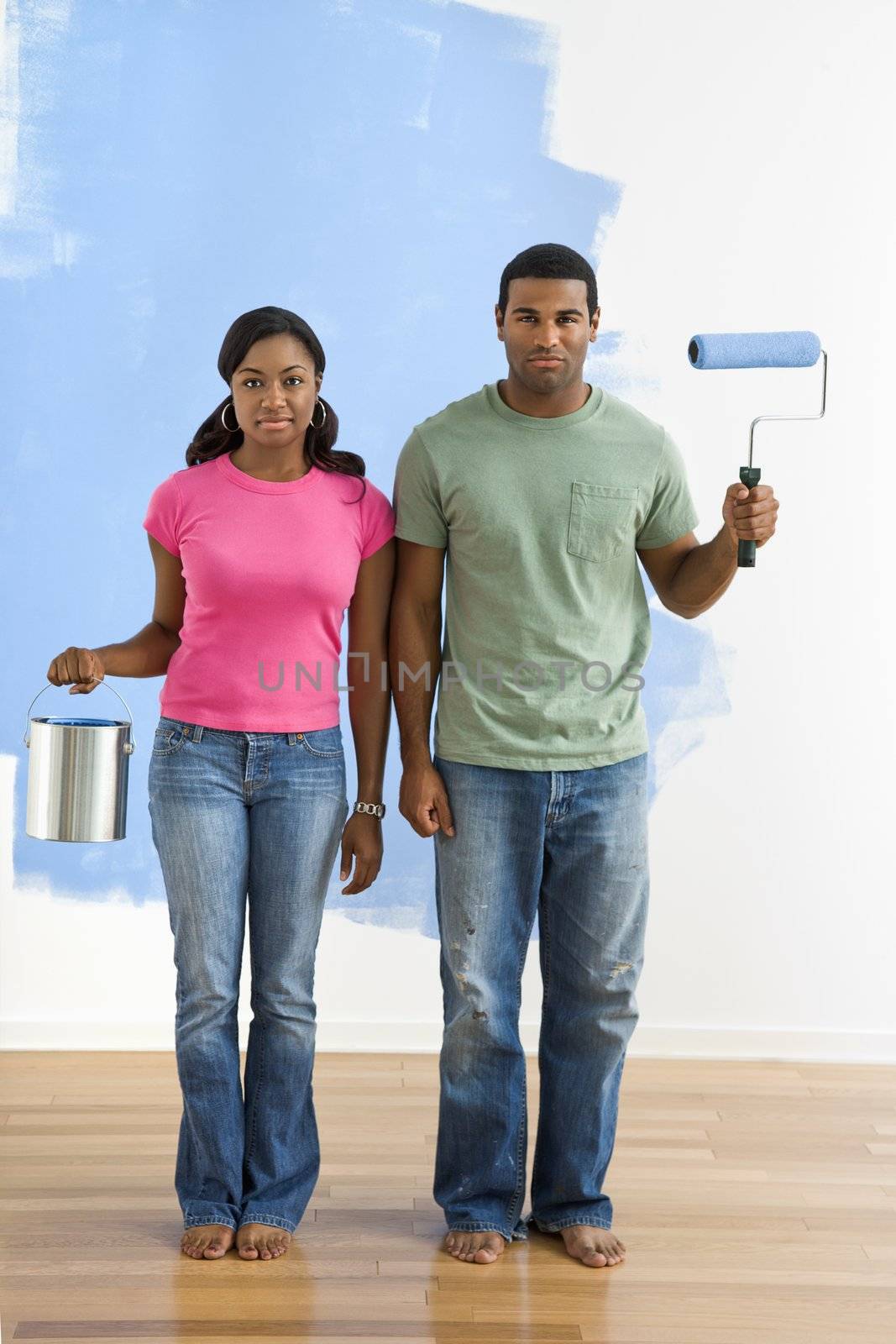 African American couple next to half-painted wall with paint supplies-American Gothic-style.