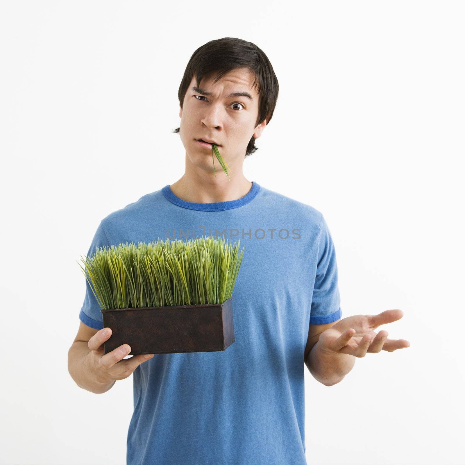Man holding pot of grass. by iofoto