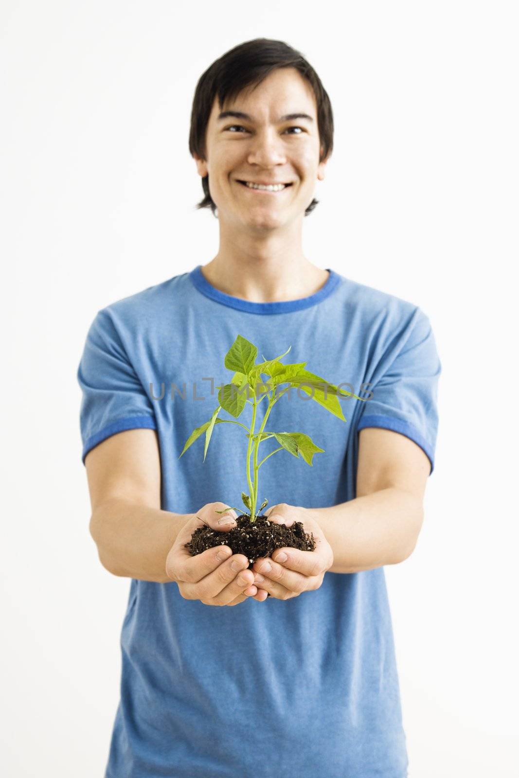 Smiling man holding plant. by iofoto