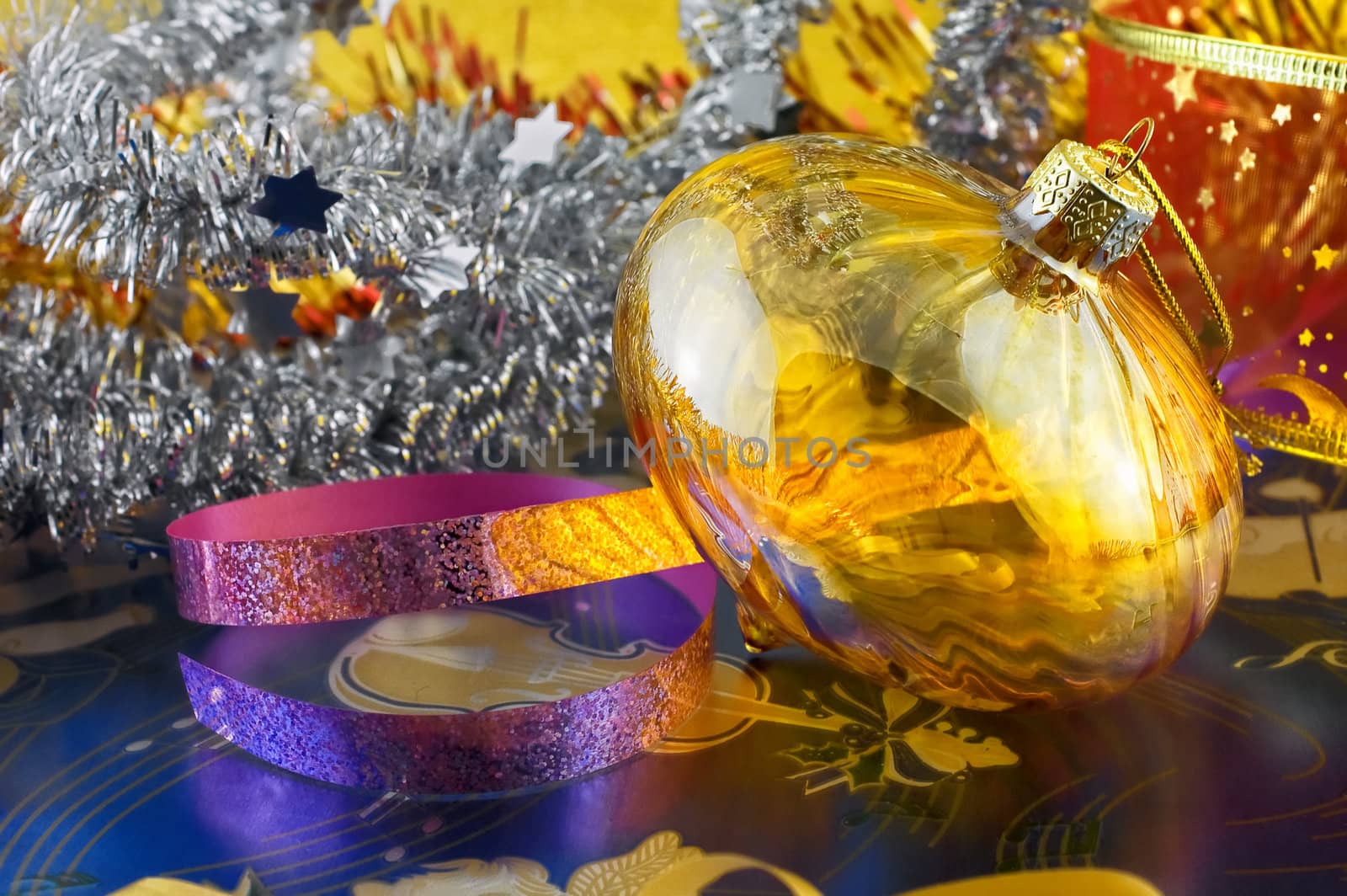 Glass Christmas bauble among tinsels and ribbons with selective focus