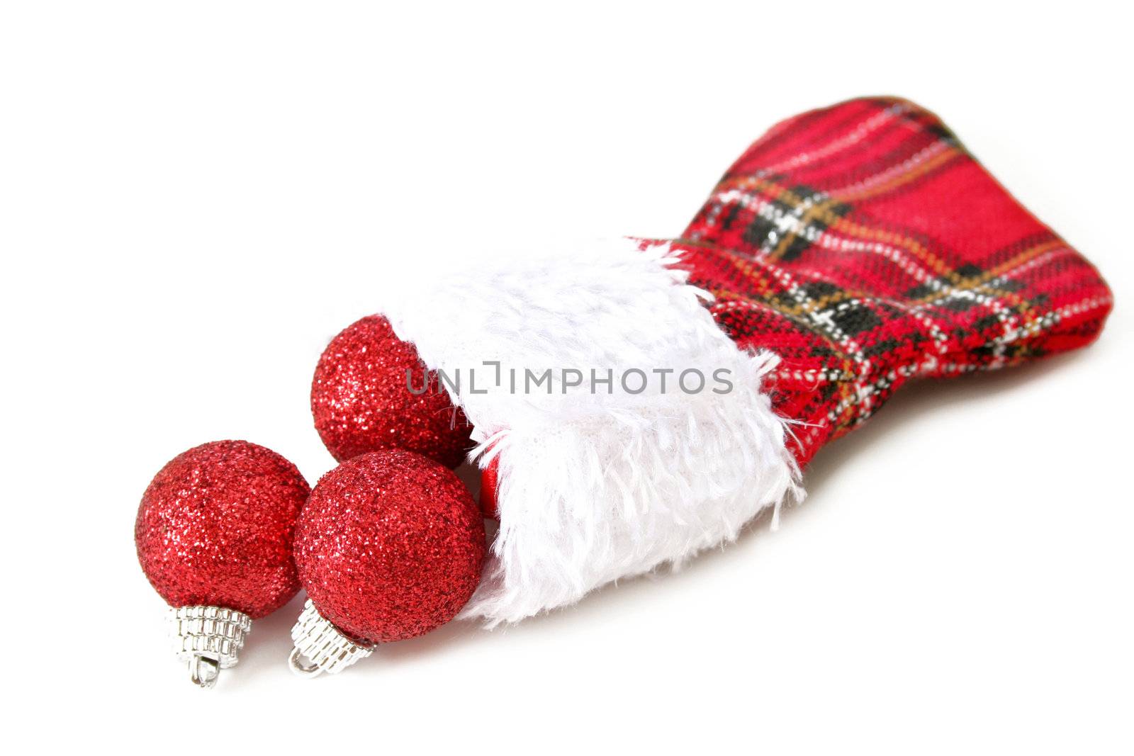 A Christmas stocking in plaid with red decorations spilling out on a white background with copy space.