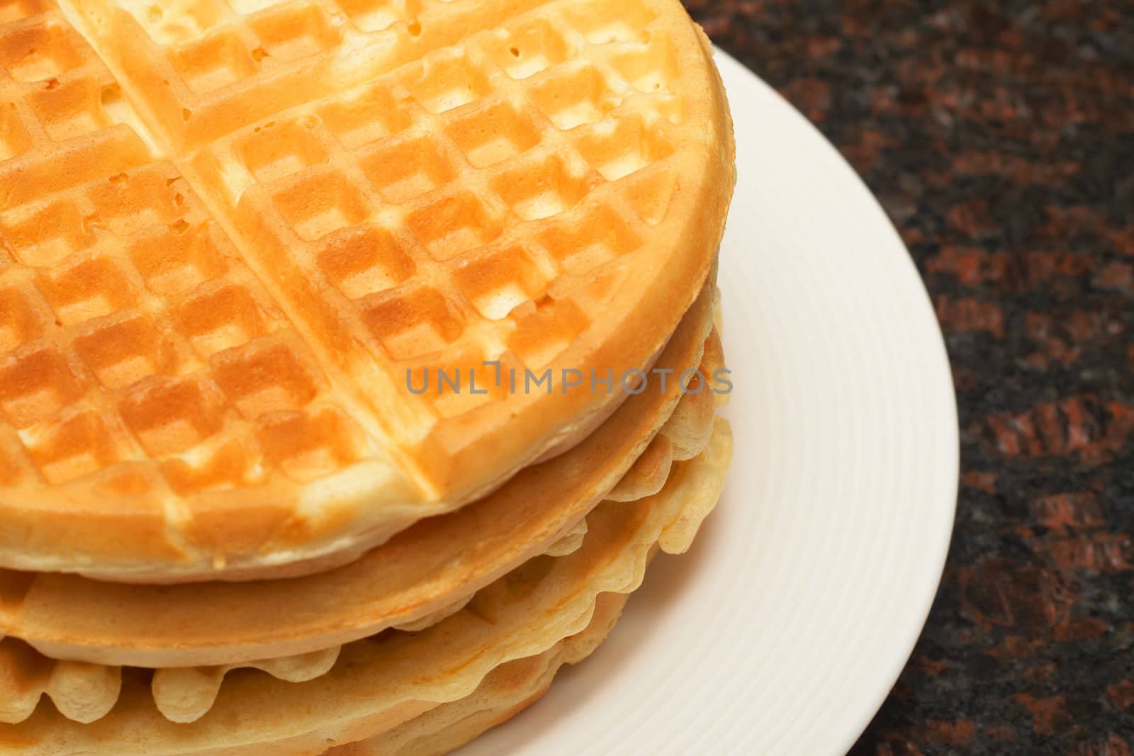 Stack of Belgian waffles on white plate