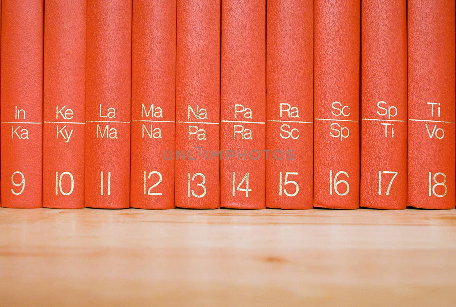 Close view on red books standing in a wooden bookshelf.